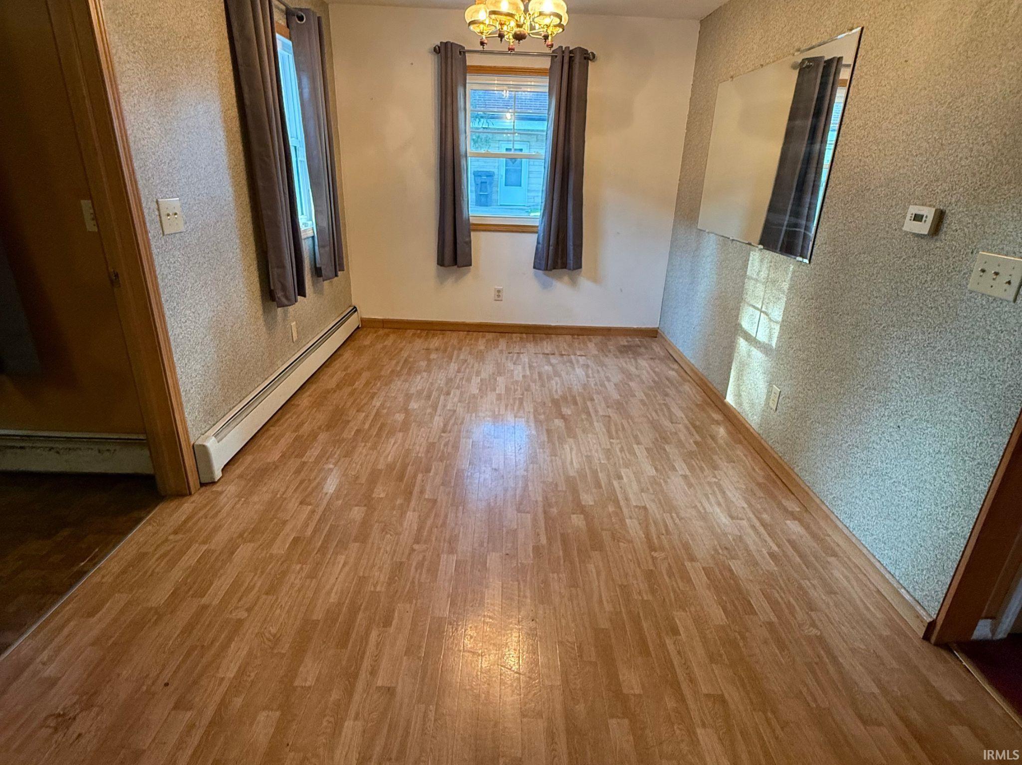 Room featuring wood-finish flooring, two windows, textured wall finishes, and a ceiling-mounted light fixture