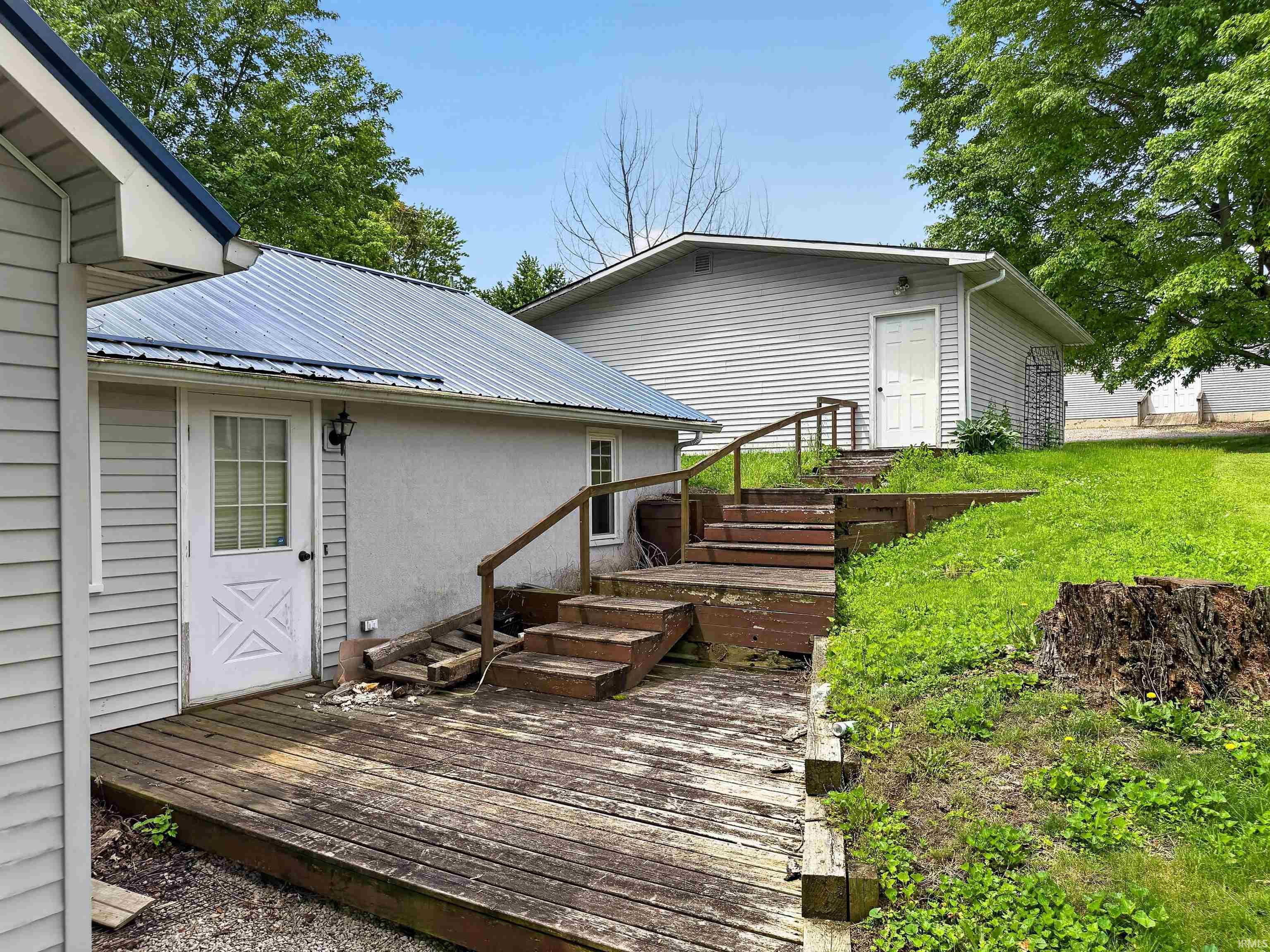 Exterior featuring light grey siding, a white paneled door with glass inserts, and a metal roof