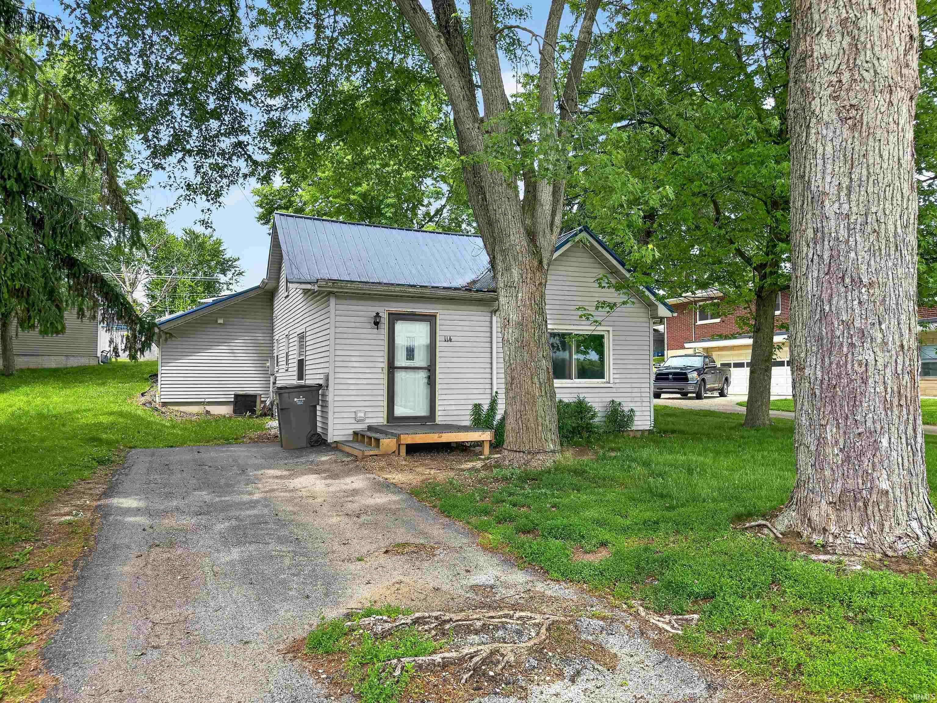 Exterior featuring light-colored siding, a metal roof, and a front entry with a screen door