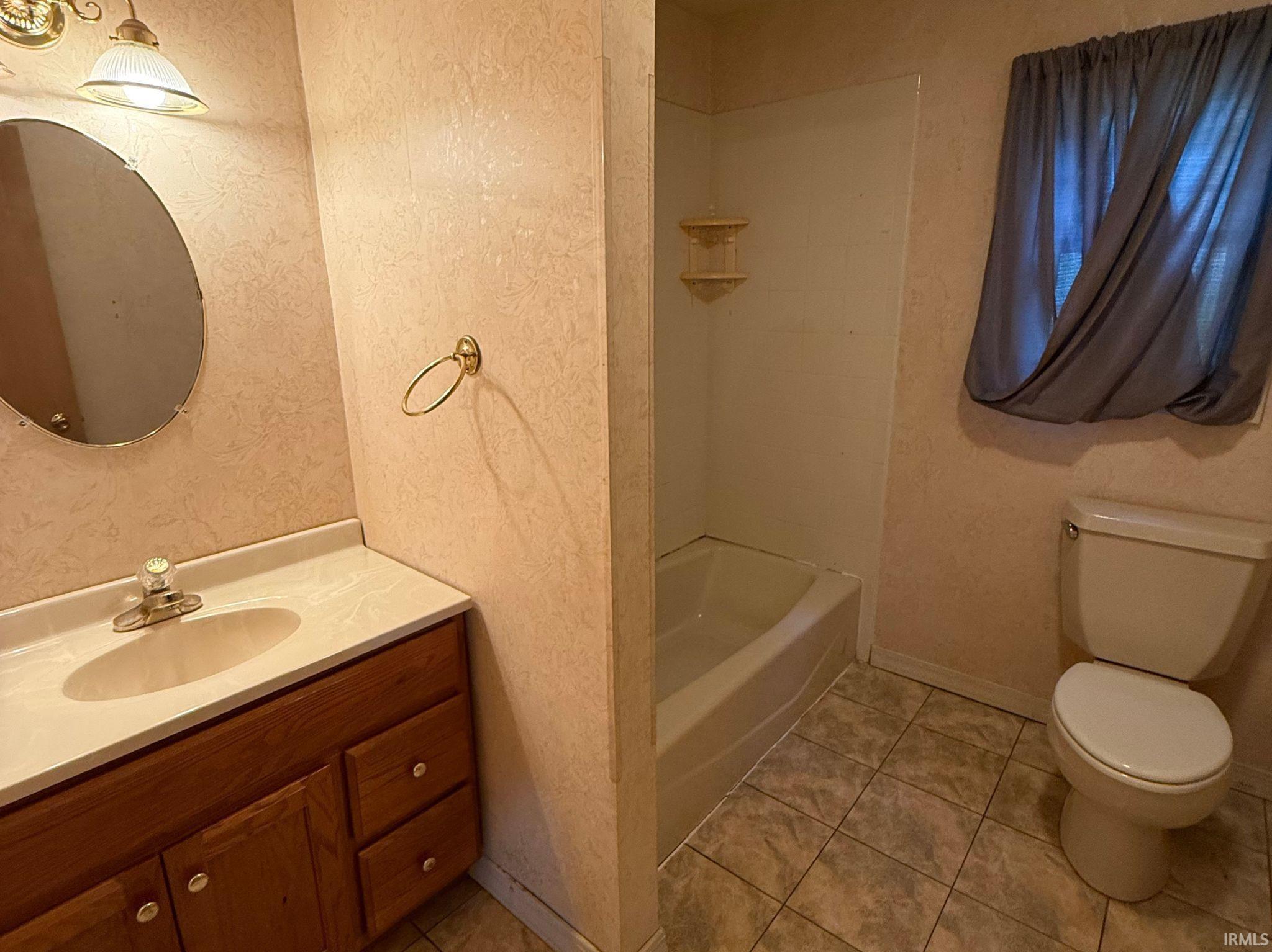 Bathroom featuring a wood-finish vanity with a single basin sink and light-colored countertop