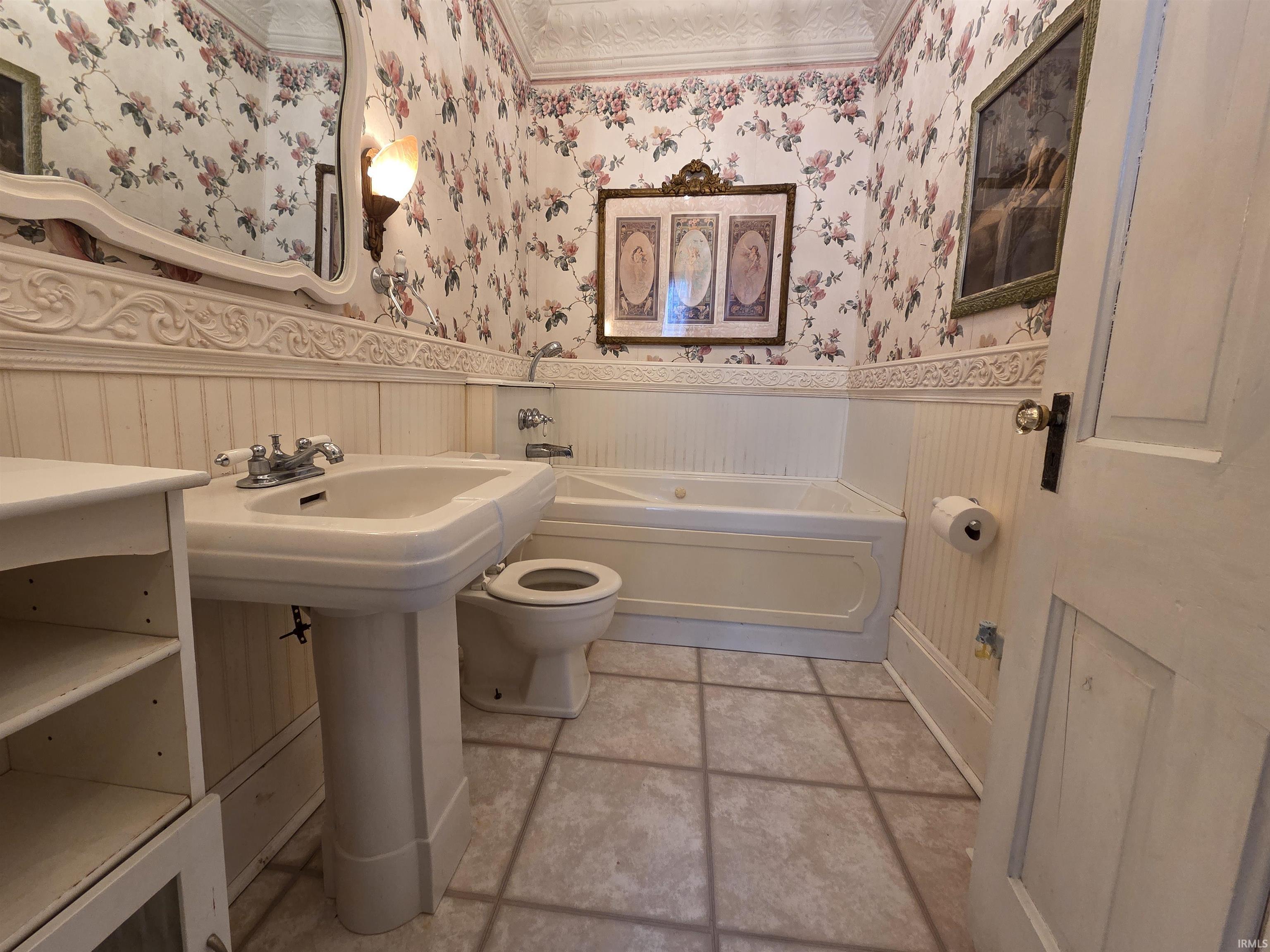 Full bath featuring a wainscoted wall, a bath, wallpapered walls, and light tile patterned flooring