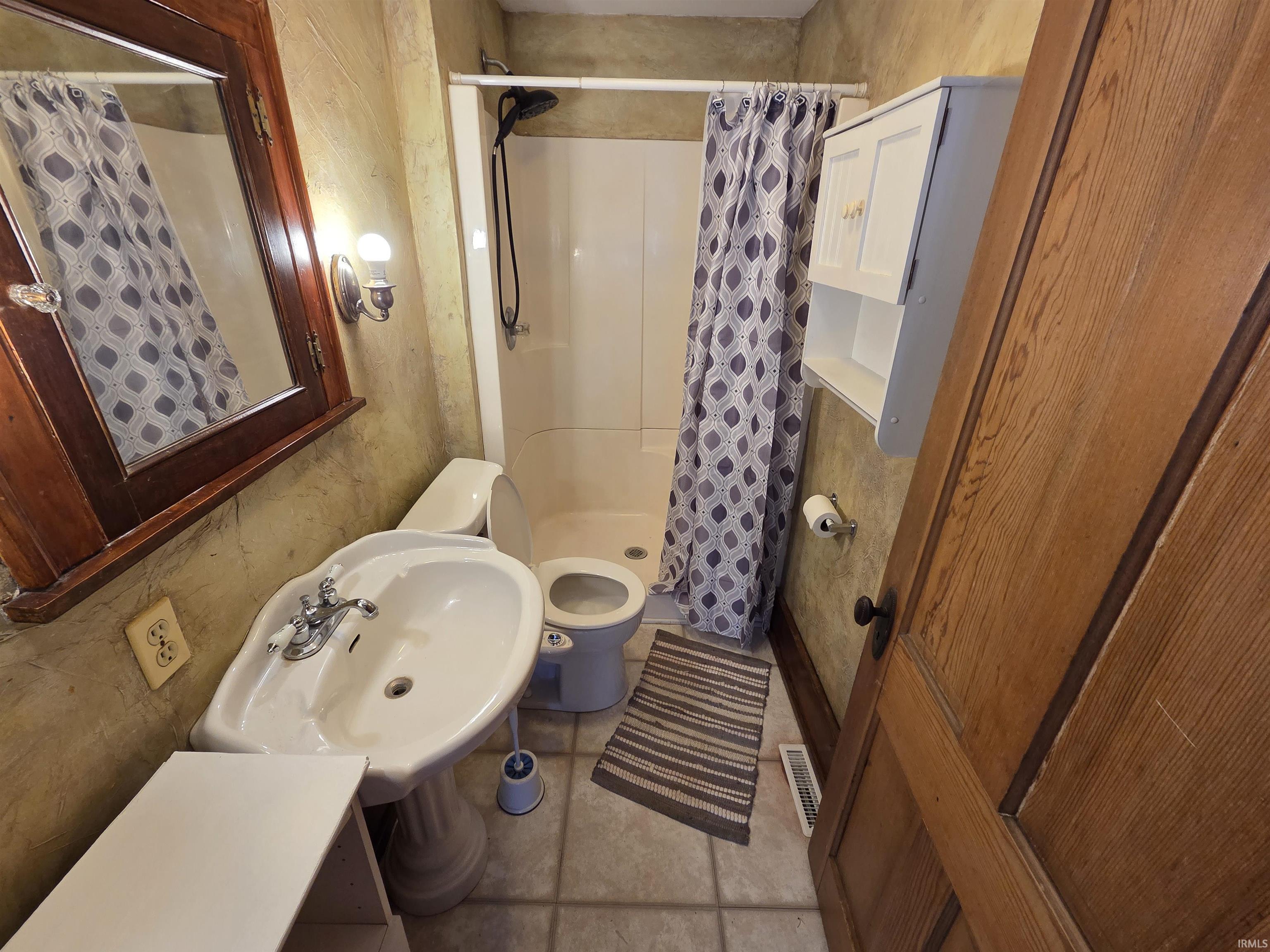 Bathroom featuring a stall shower and light tile patterned flooring