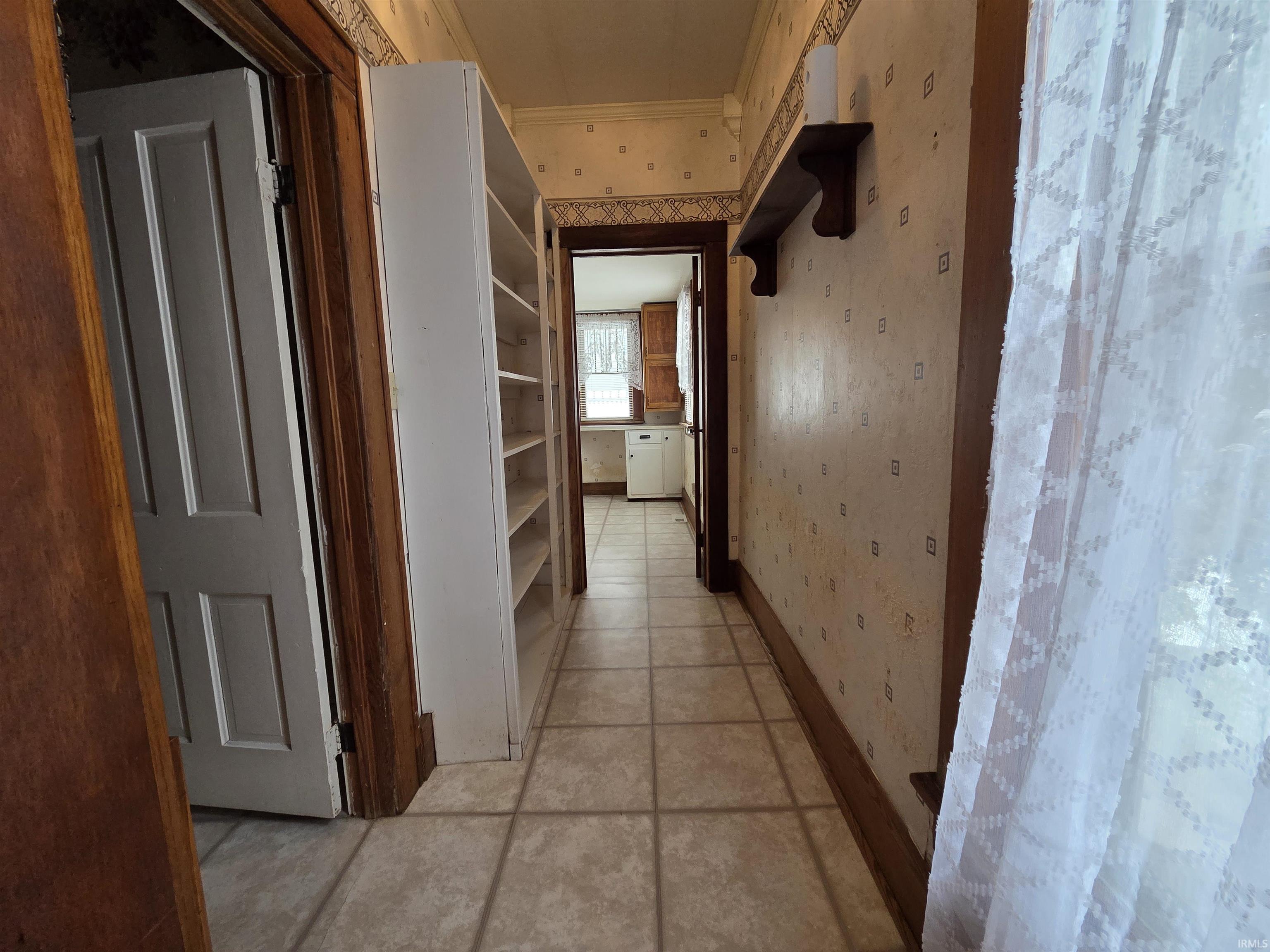 Hall featuring wallpapered walls, ornamental molding, and light tile patterned floors