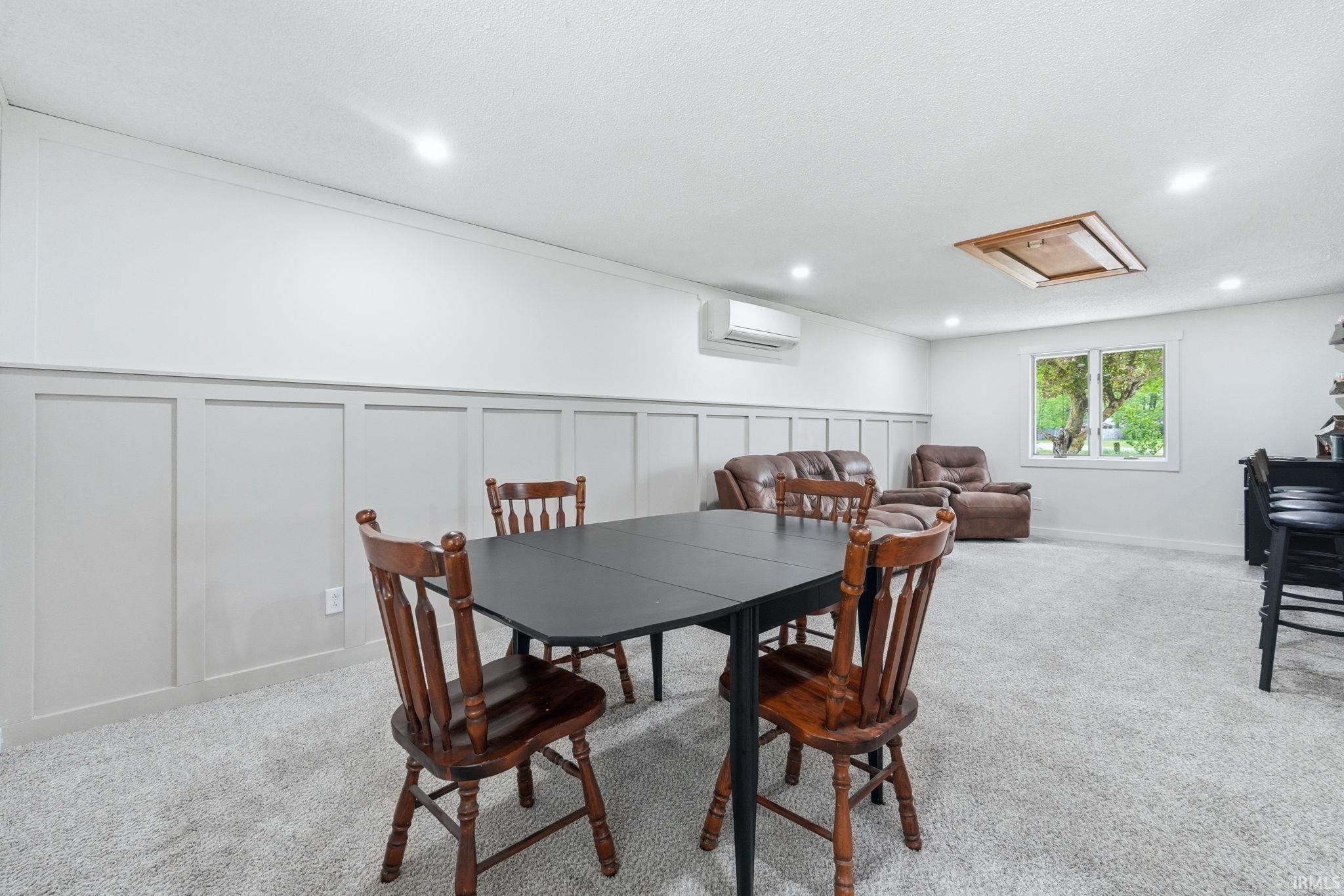 Carpeted room featuring wainscoting, recessed lighting, and a window