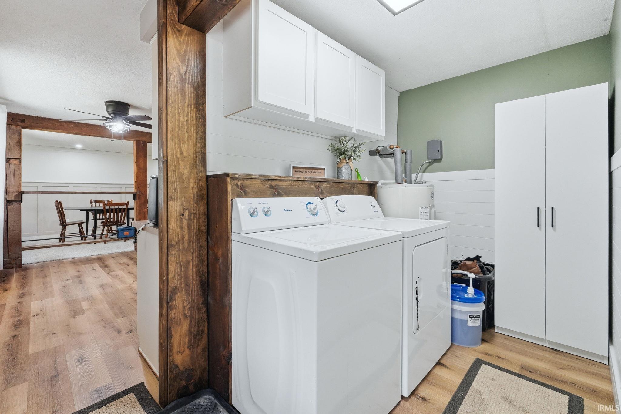 Dedicated laundry area featuring white upper cabinetry, a wood-finish counter, and a tall storage cabinet