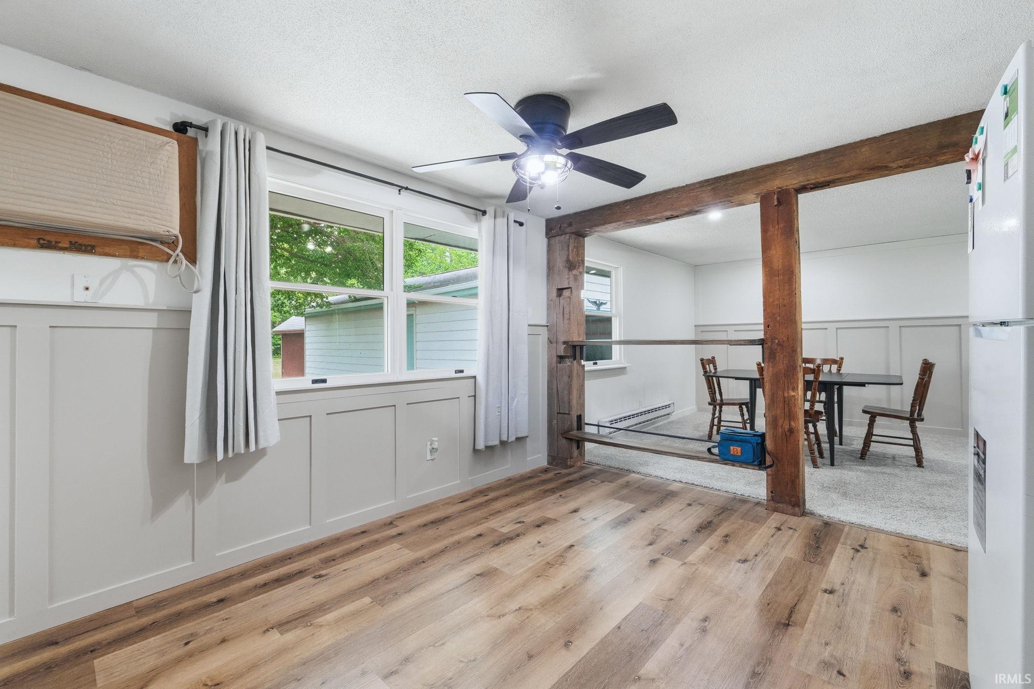 Spacious interior featuring wood-finish flooring, white board and batten wainscoting, and large windows