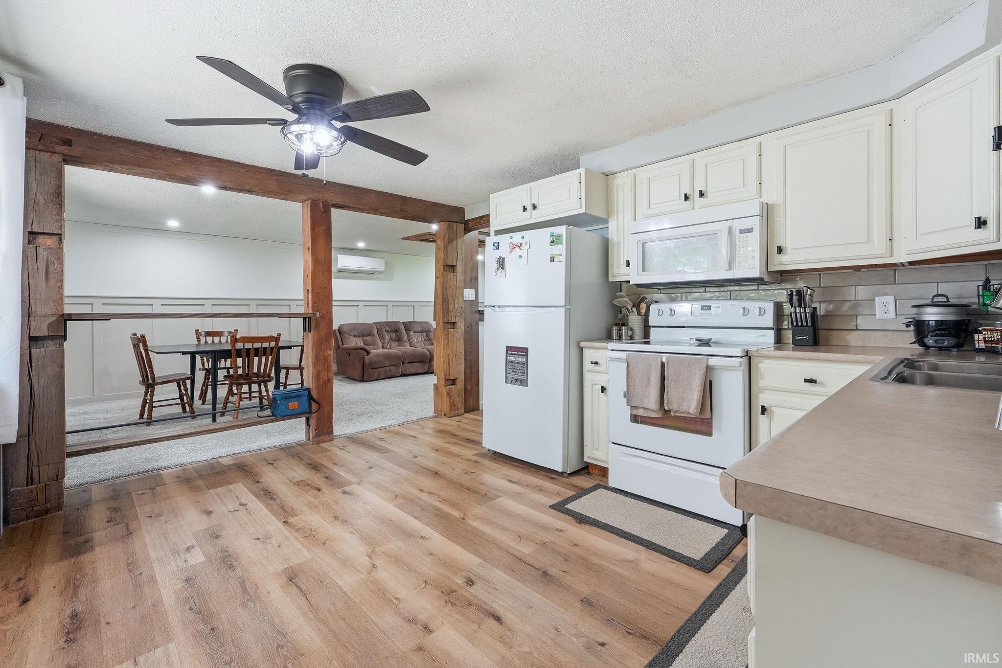 Kitchen with wood-finish flooring, white cabinetry, and light-toned countertops