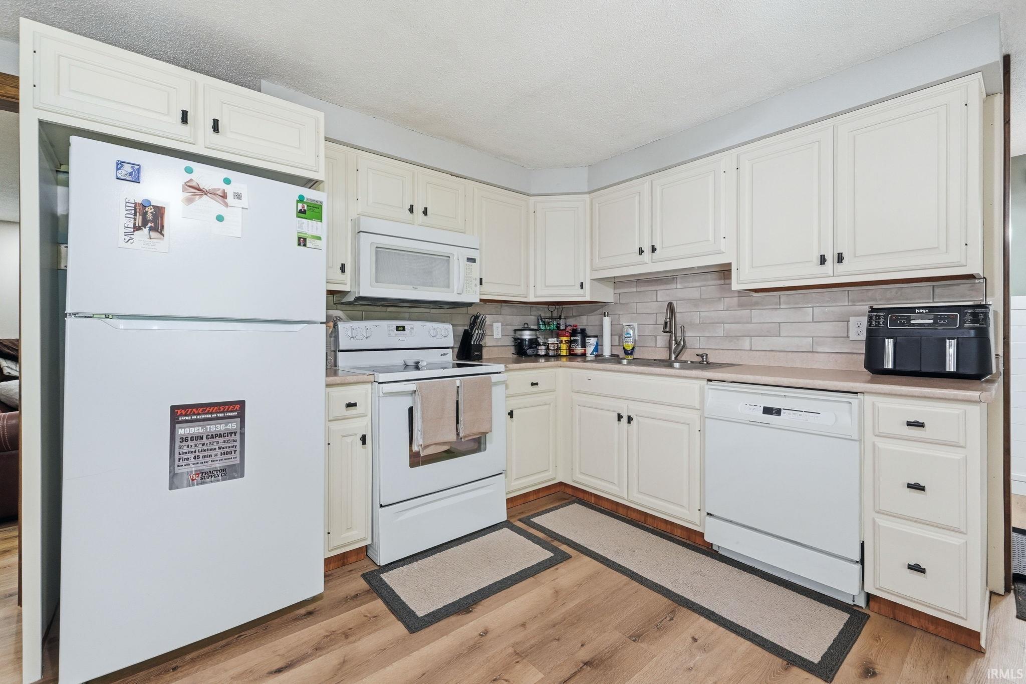 Kitchen featuring wood-finish flooring and cream-colored cabinetry with dark hardware