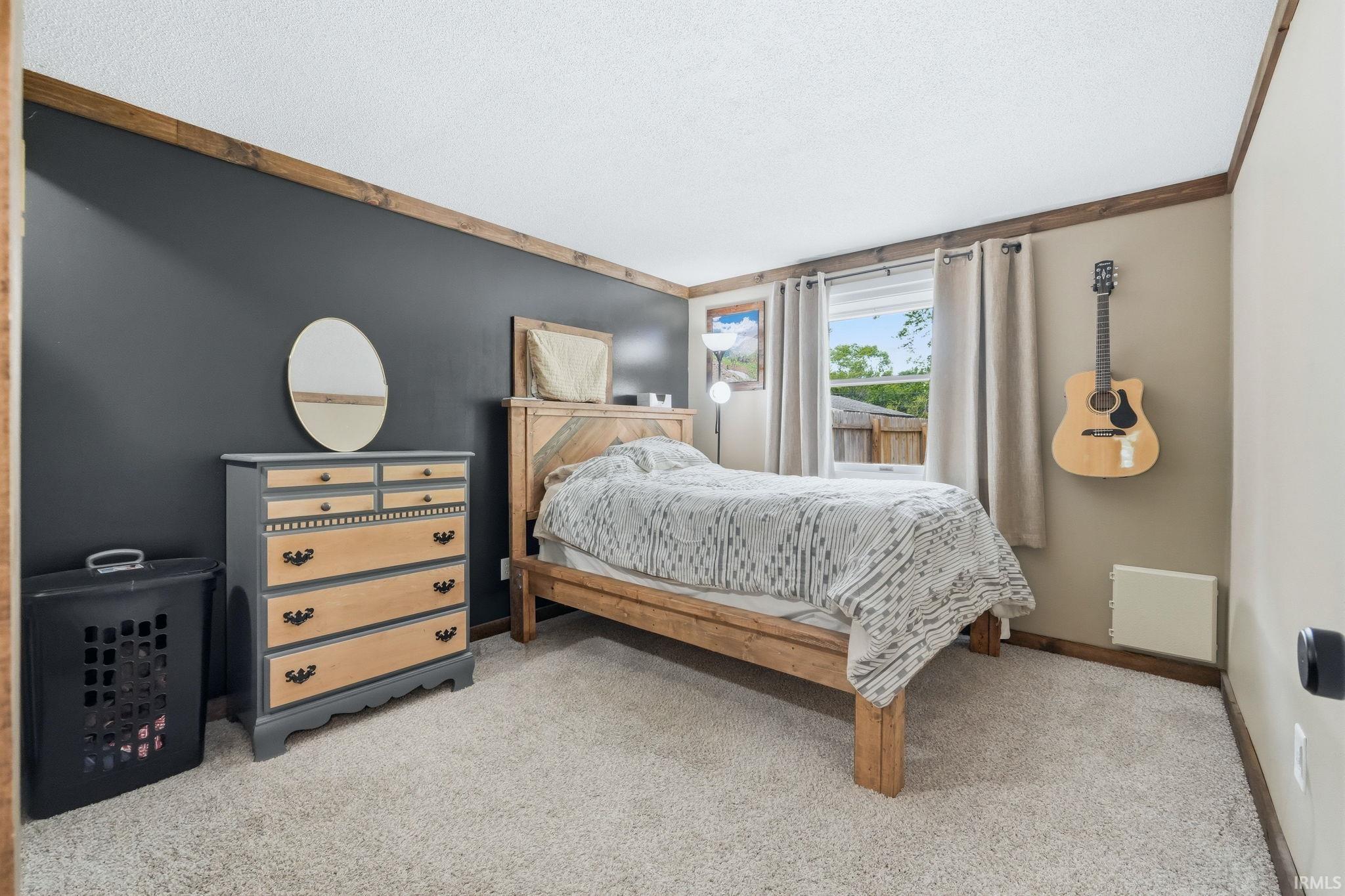 Carpeted bedroom featuring wood-finish trim, a window with curtains, and neutral wall tones