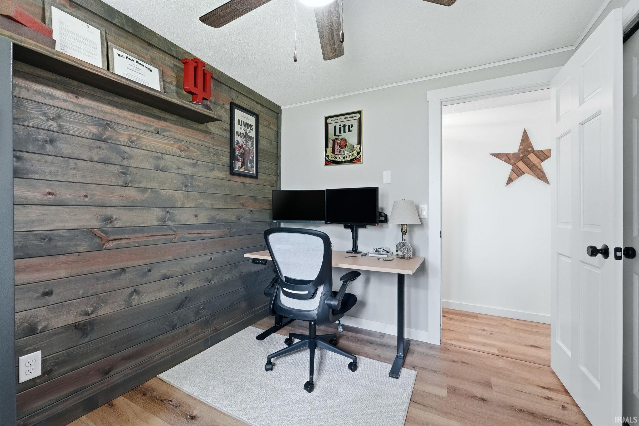 Accent wall with horizontal wood paneling, wood-finish flooring, and a ceiling fan