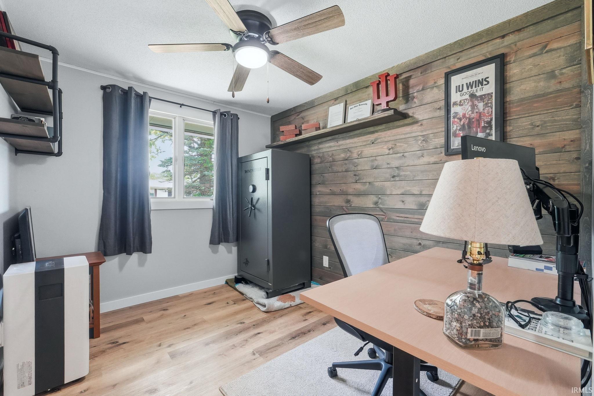 Room featuring wood-finish flooring, a ceiling fan with integrated lighting, and a window with a white frame