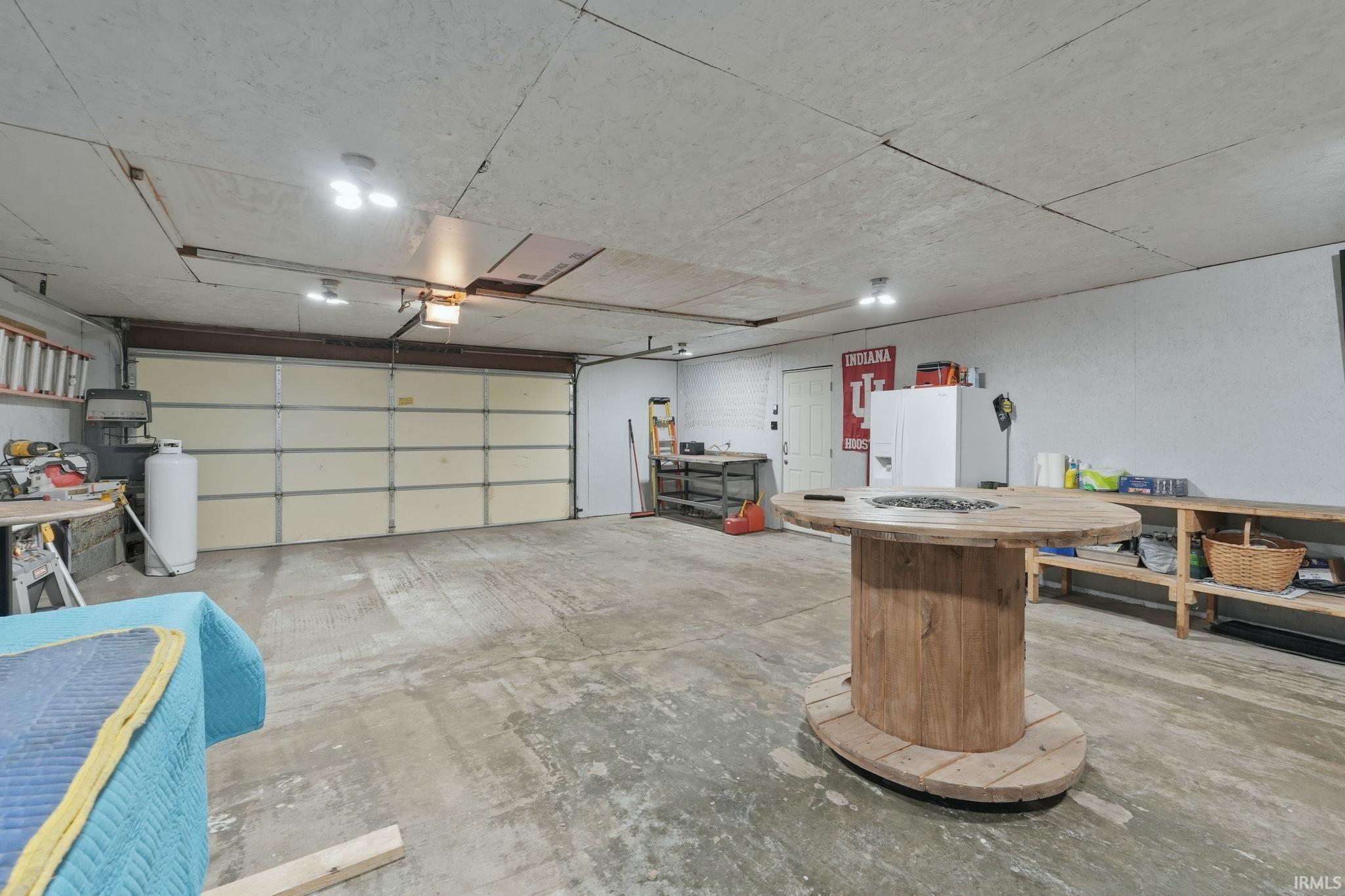 Spacious garage featuring a large overhead door, concrete flooring, and multiple ceiling-mounted light fixtures