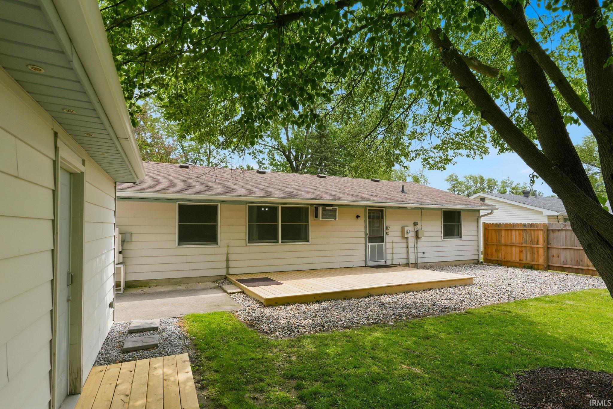 Private backyard featuring a wood deck, gravel landscaping, and a wood fence