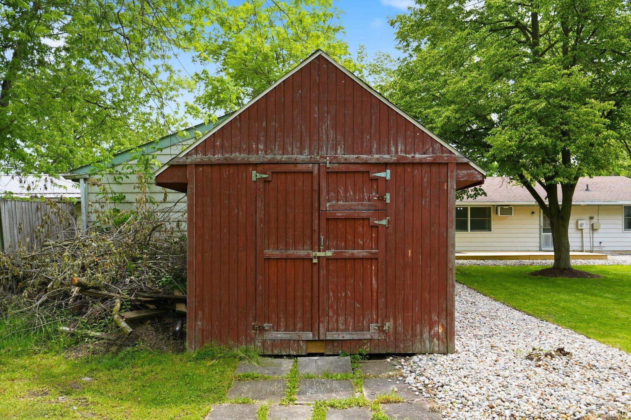 Red wood-paneled storage shed with a gabled roof