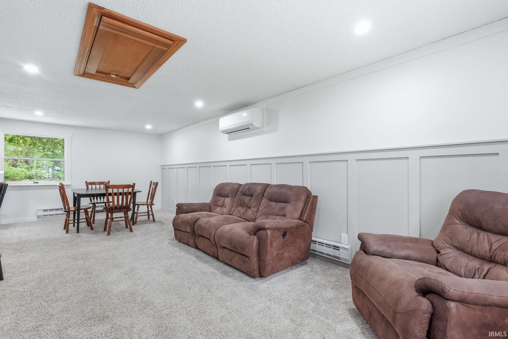 Spacious room featuring light gray carpeting, recessed lighting, and a window offering natural illumination