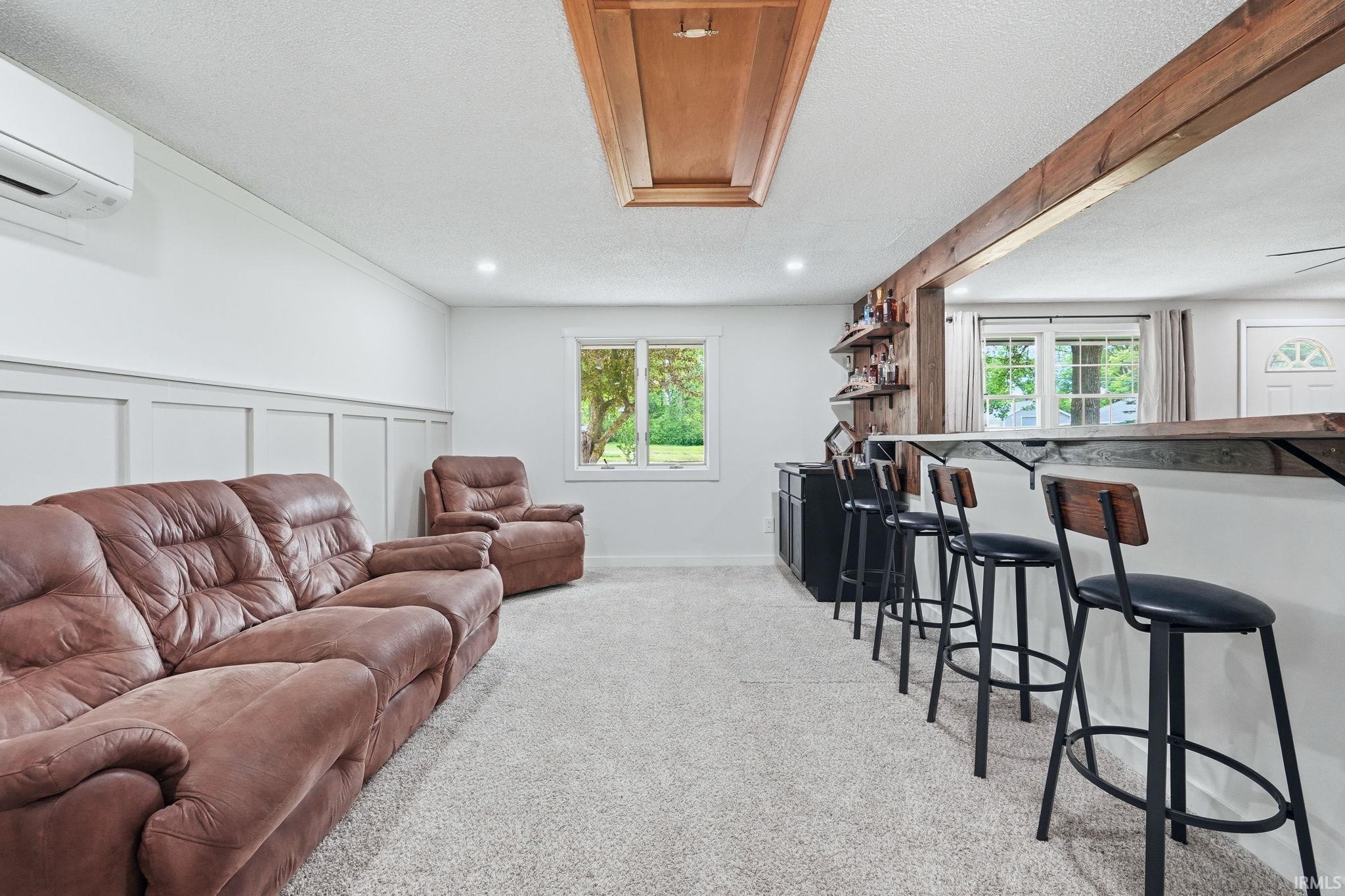 Carpeted entertainment area featuring wainscoting, recessed lighting, and a built-in bar with wood-finish shelving