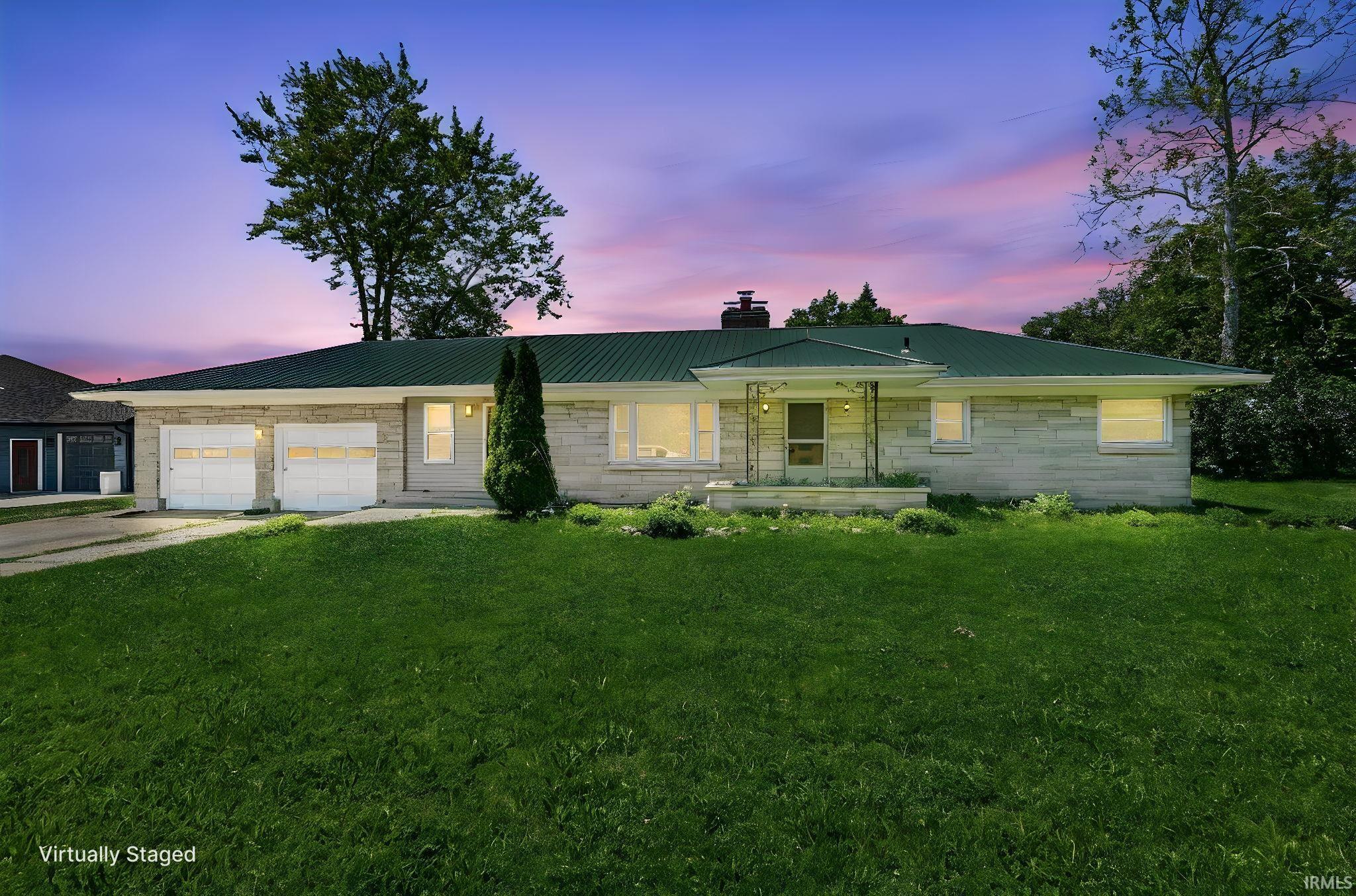 Ranch-style residence featuring a stone exterior, green metal roof, and a two-car attached garage