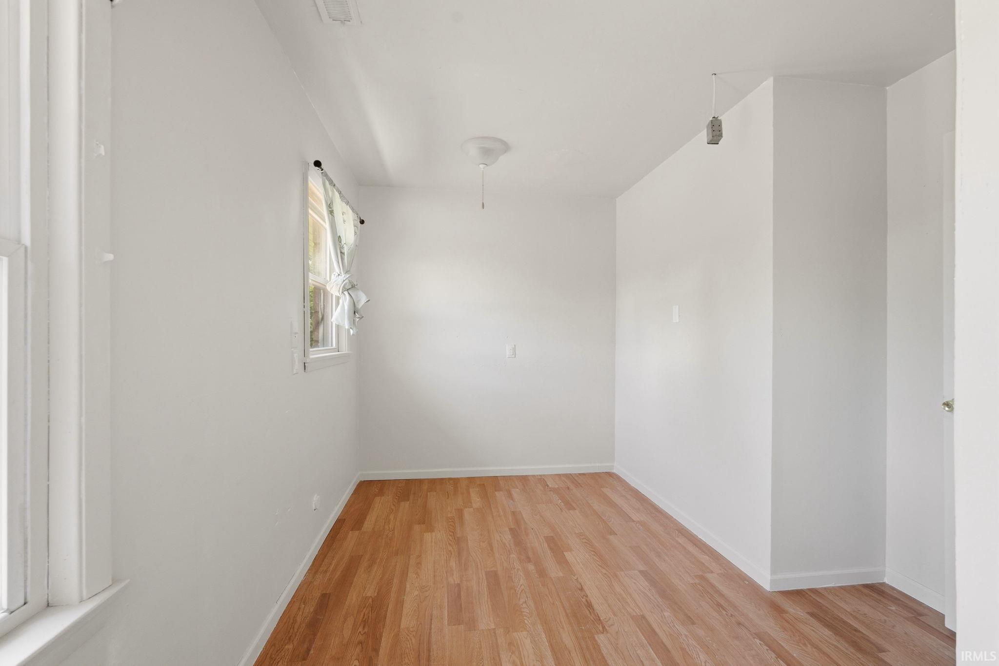 Bright interior space featuring wood-finish flooring, white walls, and a window with natural light
