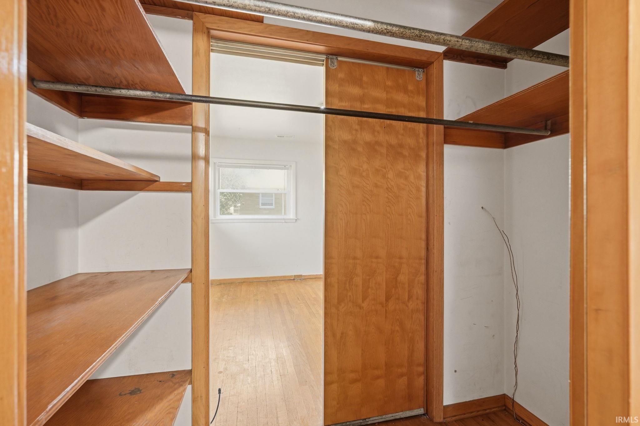 Closet interior featuring a sliding wood door and wood-finish shelving