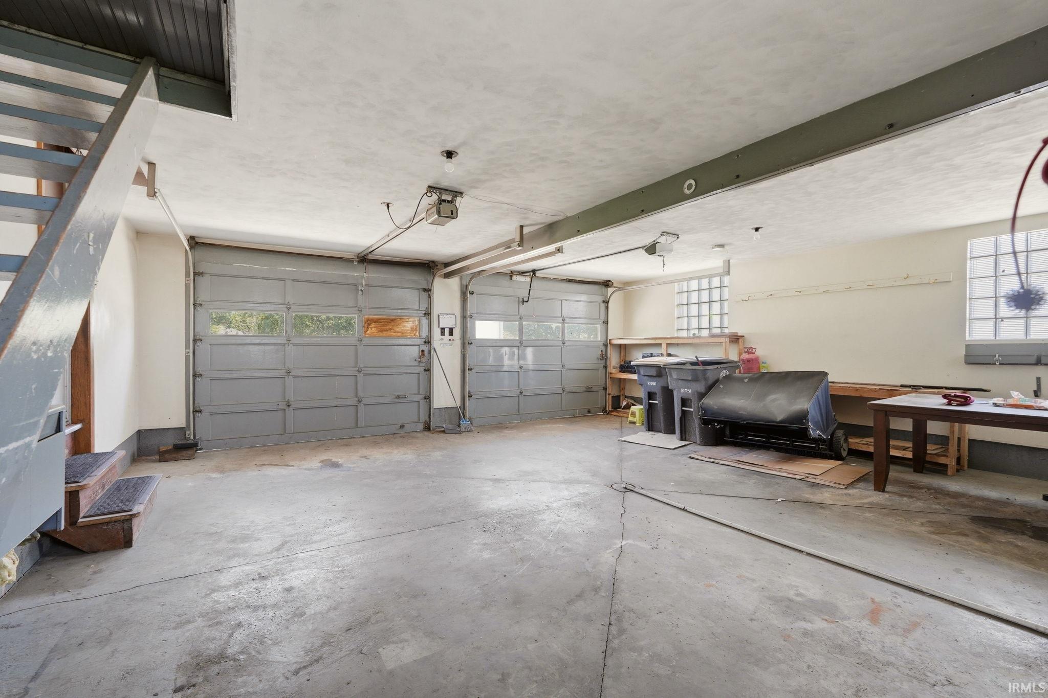 Spacious garage featuring two overhead doors with window panels, concrete flooring, and multiple glass block windows providing natural light