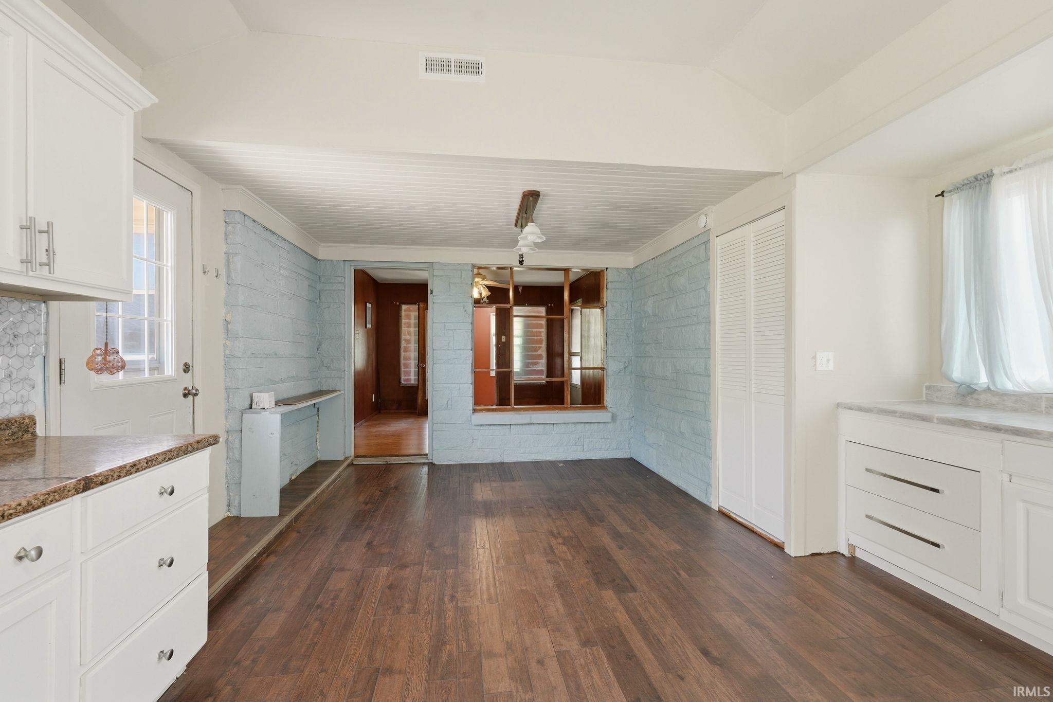 Spacious interior featuring wood-finish flooring, white cabinetry with contemporary hardware, and a tile backsplash