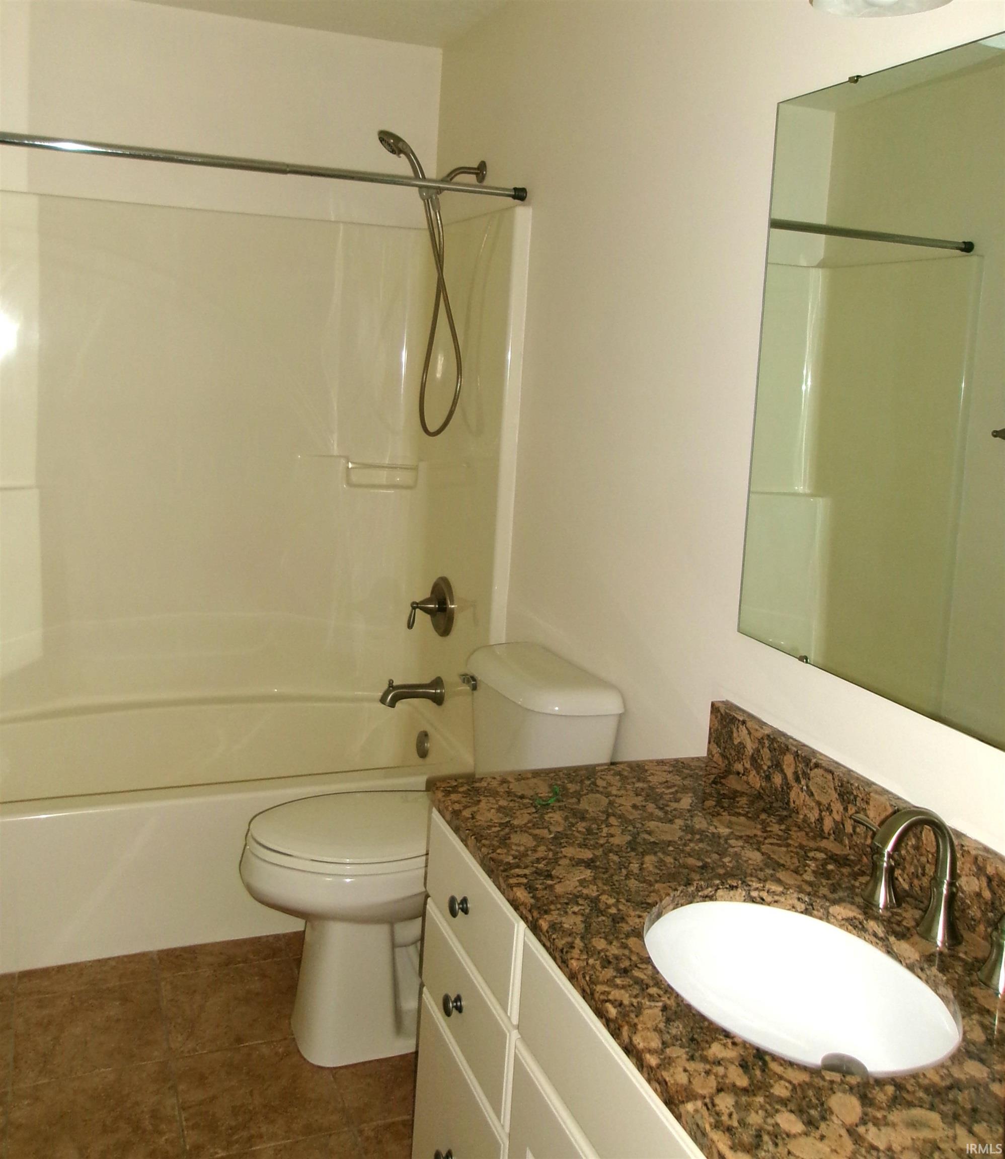 Bathroom featuring a white vanity with multiple drawers, a speckled countertop, an undermount sink with a brushed nickel faucet, and a large wall-mounted mirror