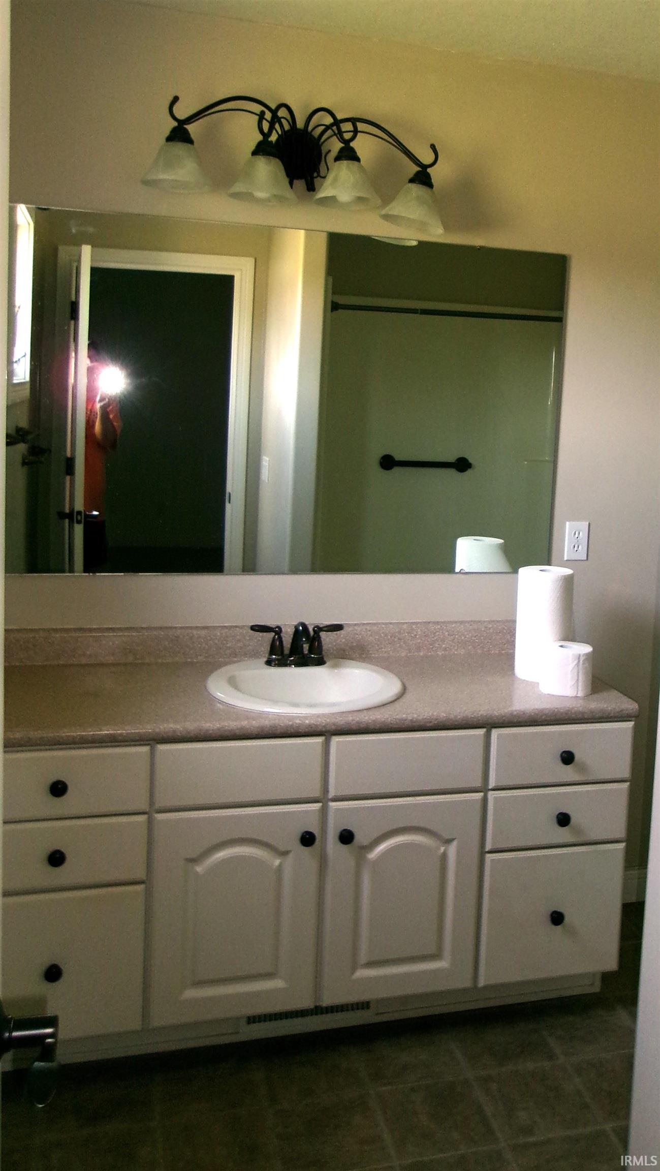 Bathroom vanity with a light-colored countertop, an oval undermount sink, and a black faucet