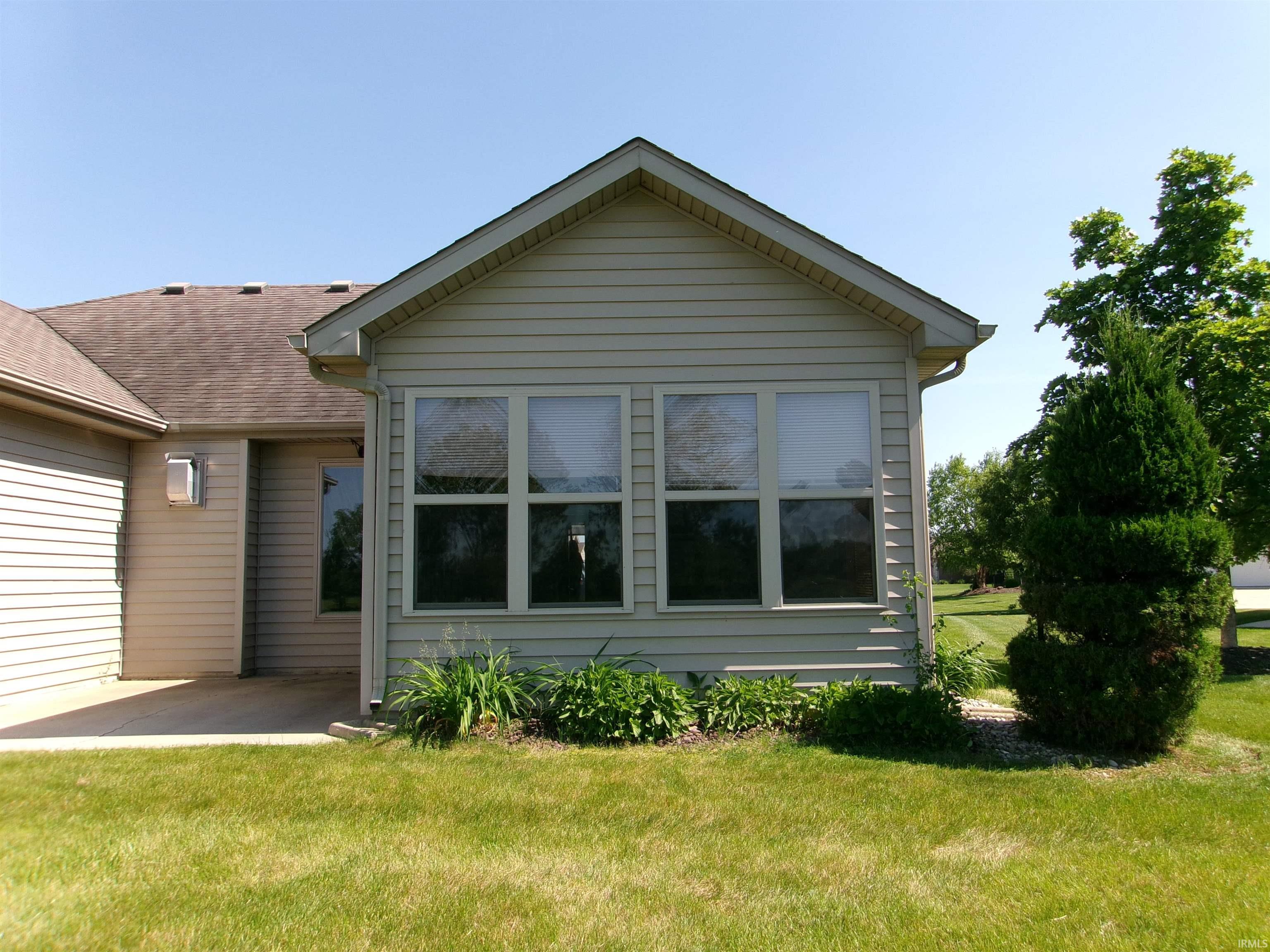 Rear exterior featuring light-toned horizontal siding, a gabled roofline, and a multi-pane window configuration