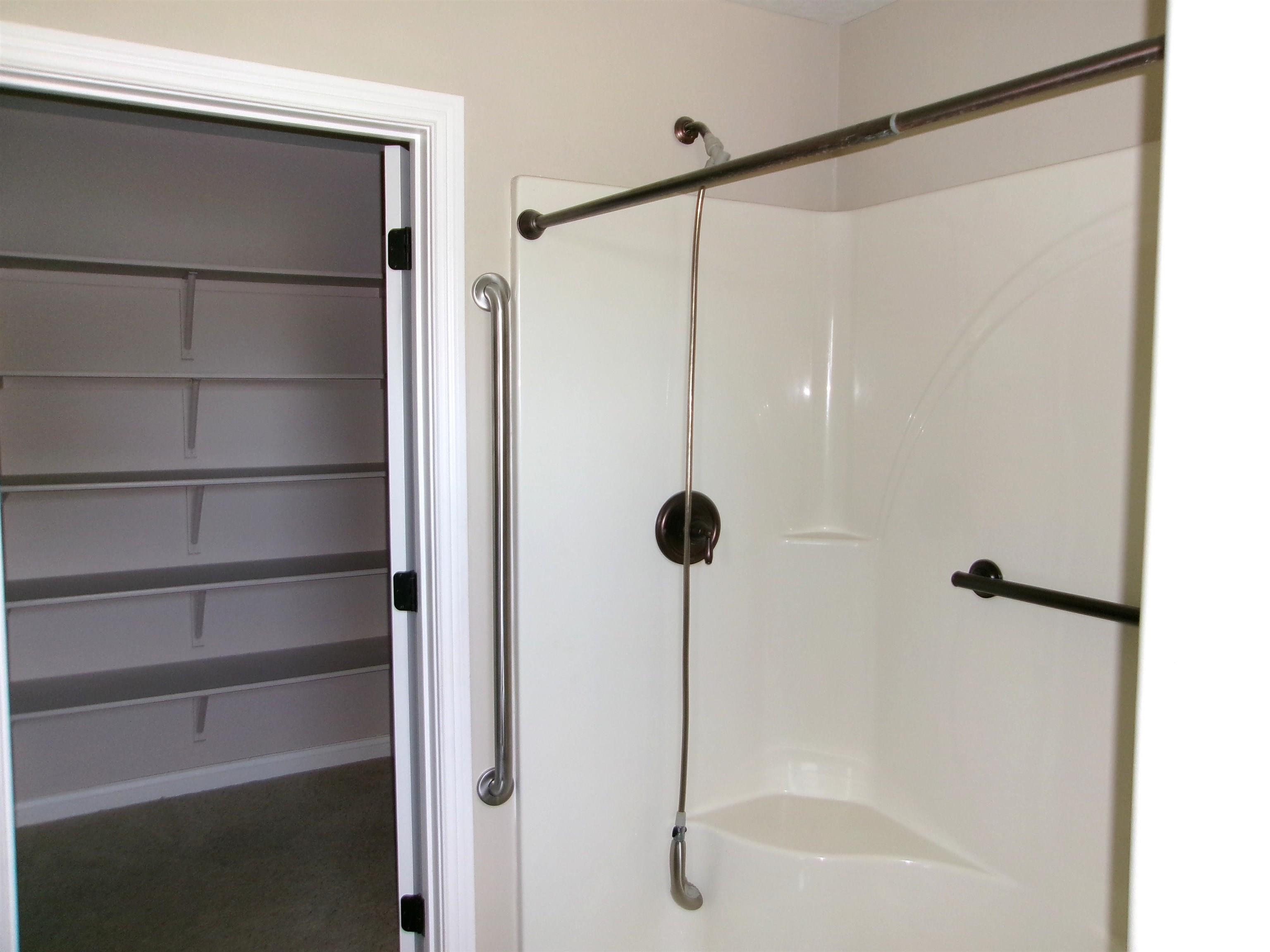 White shower enclosure with a built-in corner shelf and bronze-finish fixtures