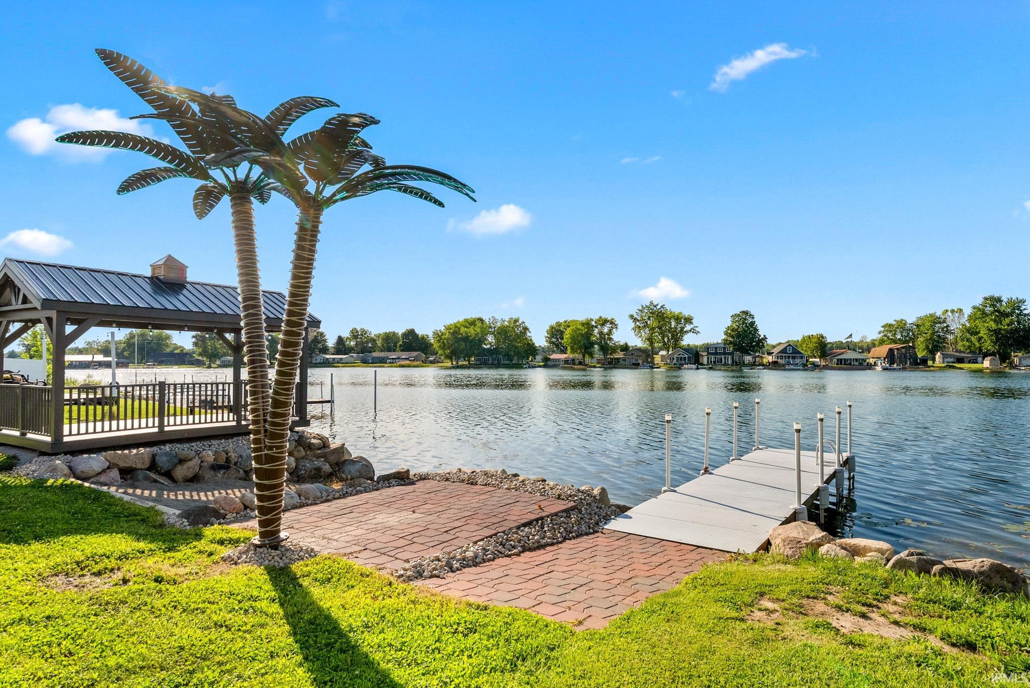 Waterfront property featuring a private dock, covered gazebo with metal roof, and a brick paver patio