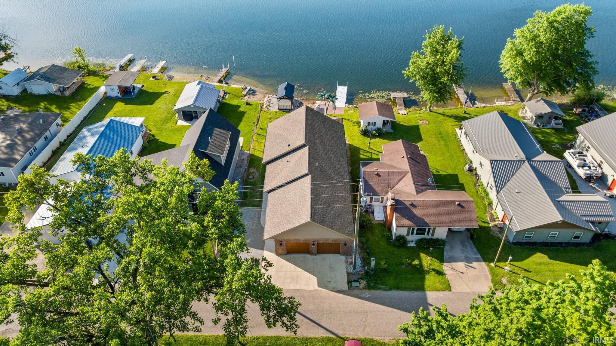 Waterfront property featuring a private boat dock, green lawn, and mature trees