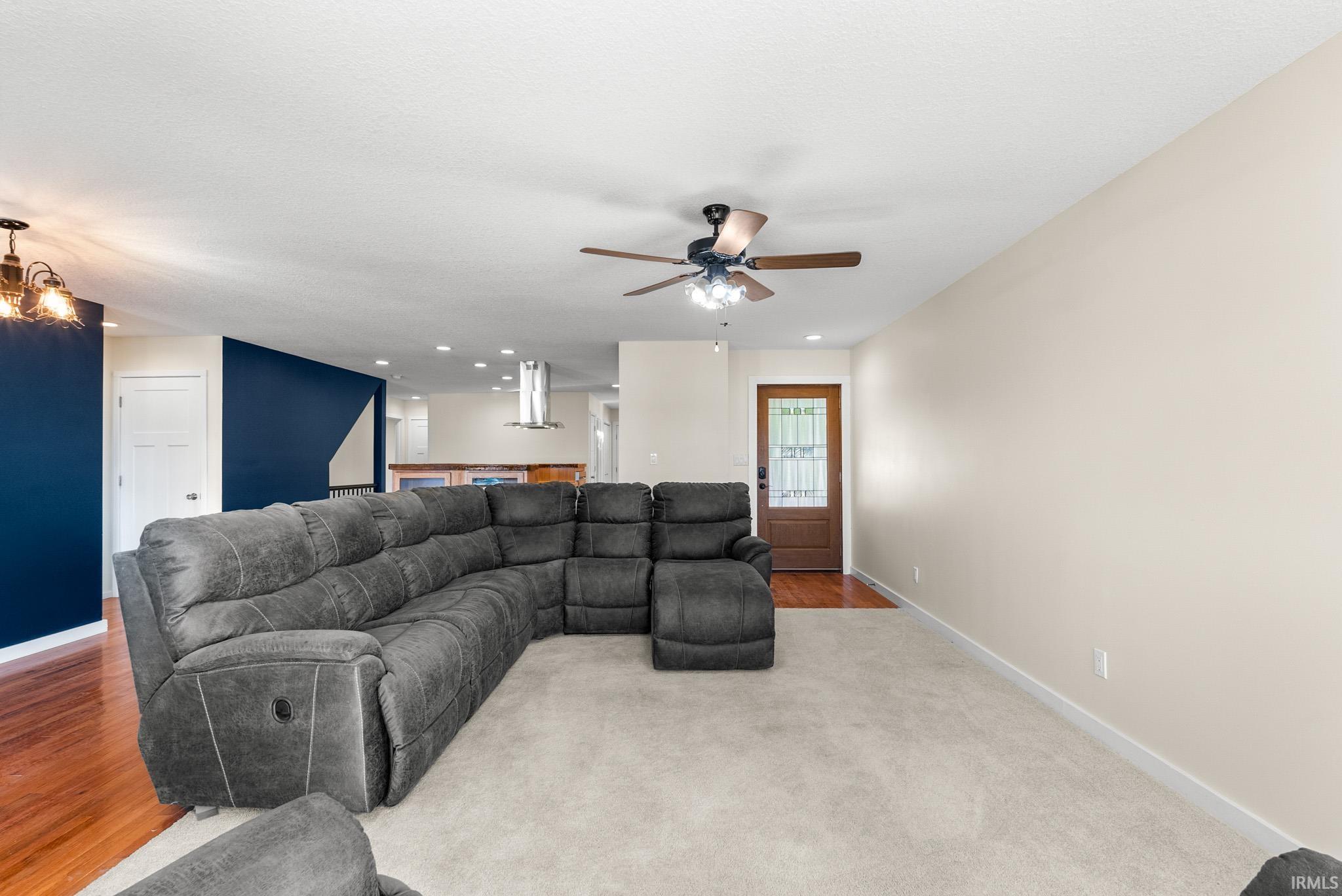 Spacious living area featuring neutral carpeting and a warm wood-finish flooring entry