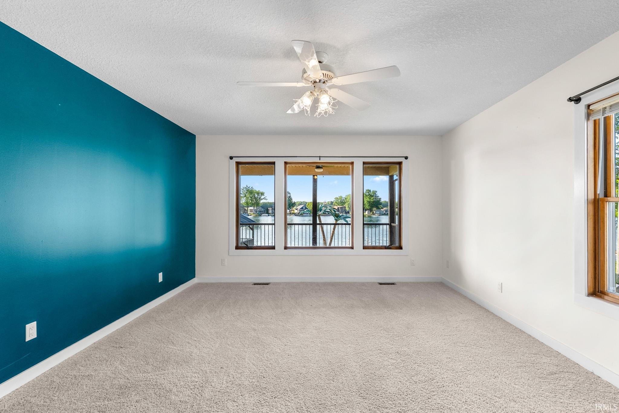 Spacious interior with neutral carpeting and white walls, featuring a bold accent wall in teal