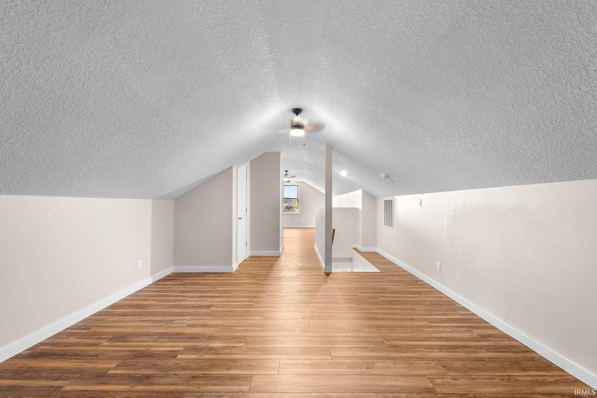 Expansive attic space featuring wood-finish flooring, vaulted ceilings, and recessed lighting