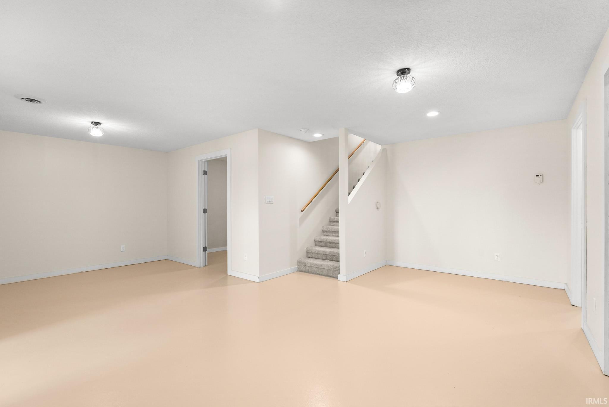 Spacious room featuring light-colored walls, recessed lighting, and a beige floor