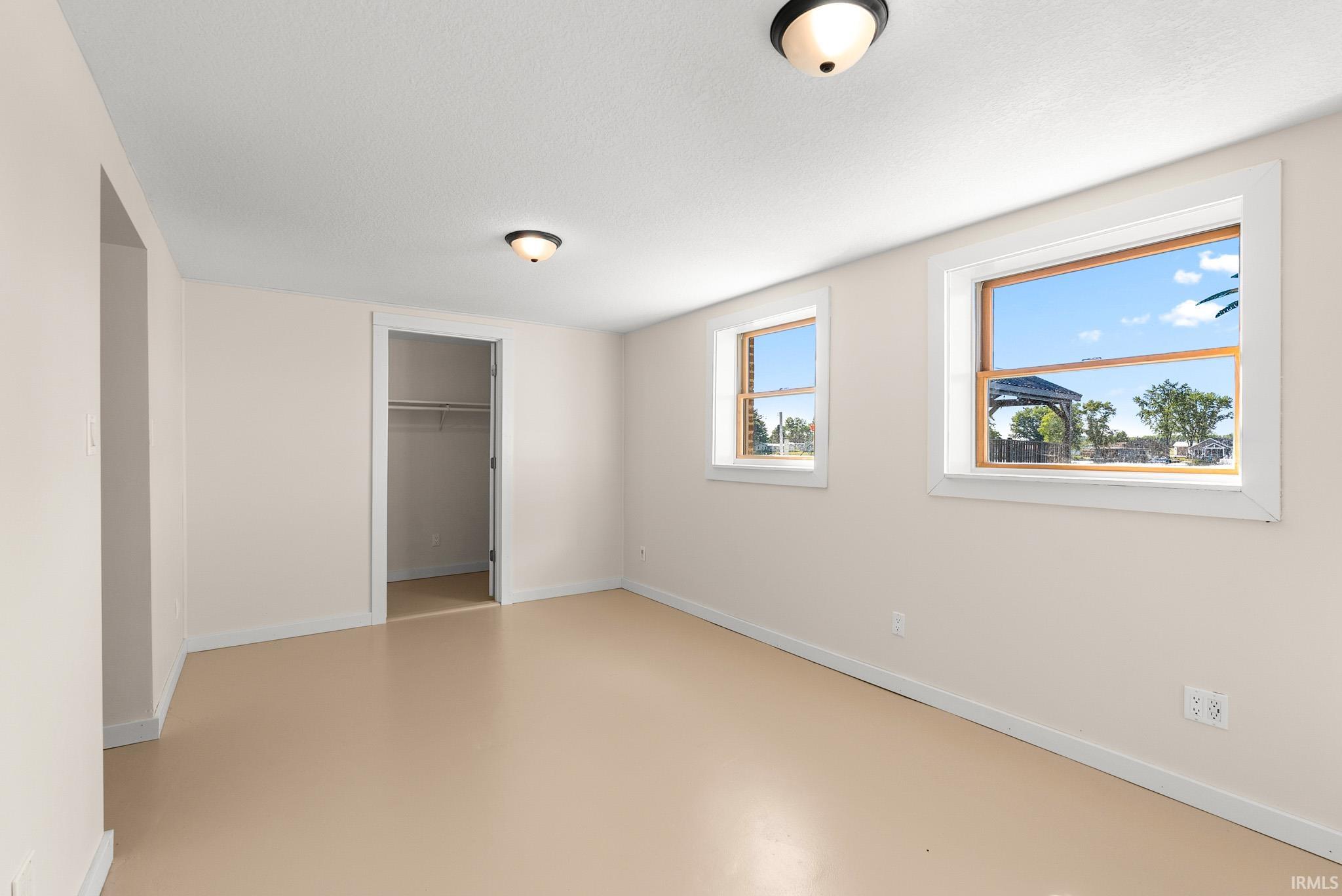Room featuring two windows, neutral painted walls, and light-colored flooring