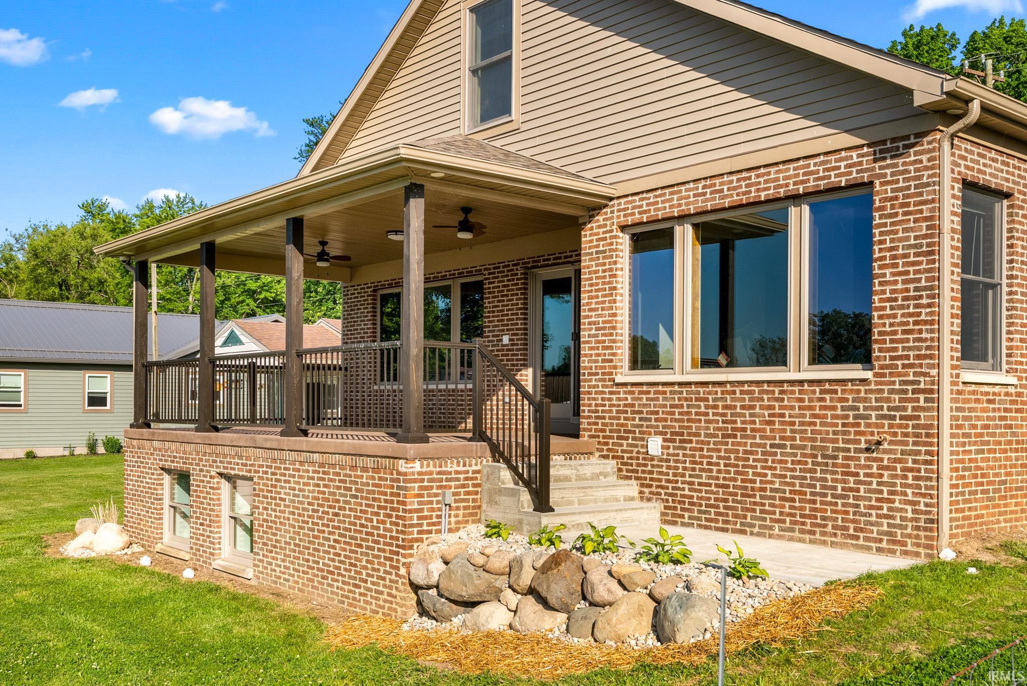 Covered porch featuring ceiling fans, dark railing, and substantial support posts
