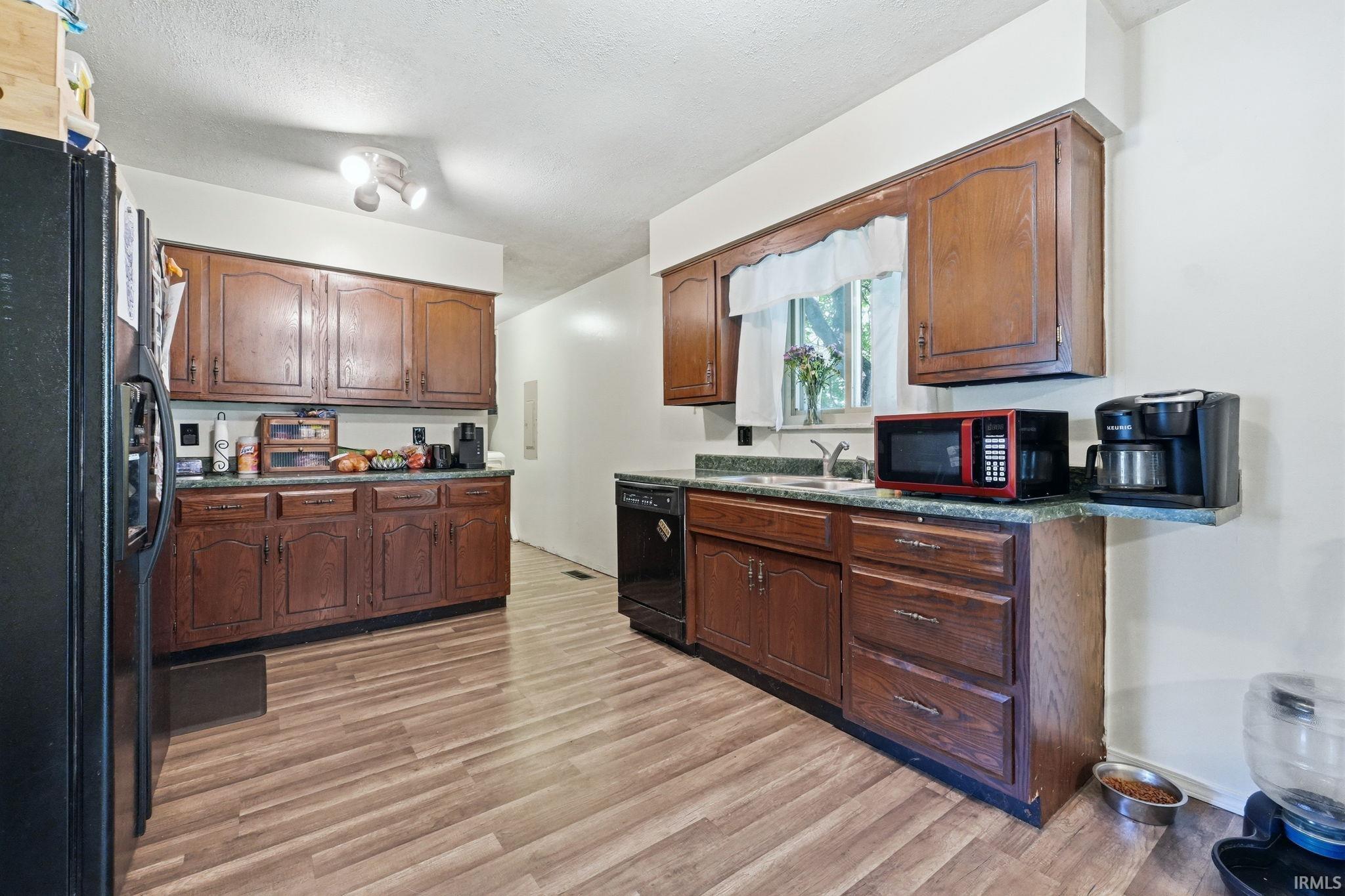 Kitchen featuring wood-finish flooring, ample cabinetry, and dark countertops
