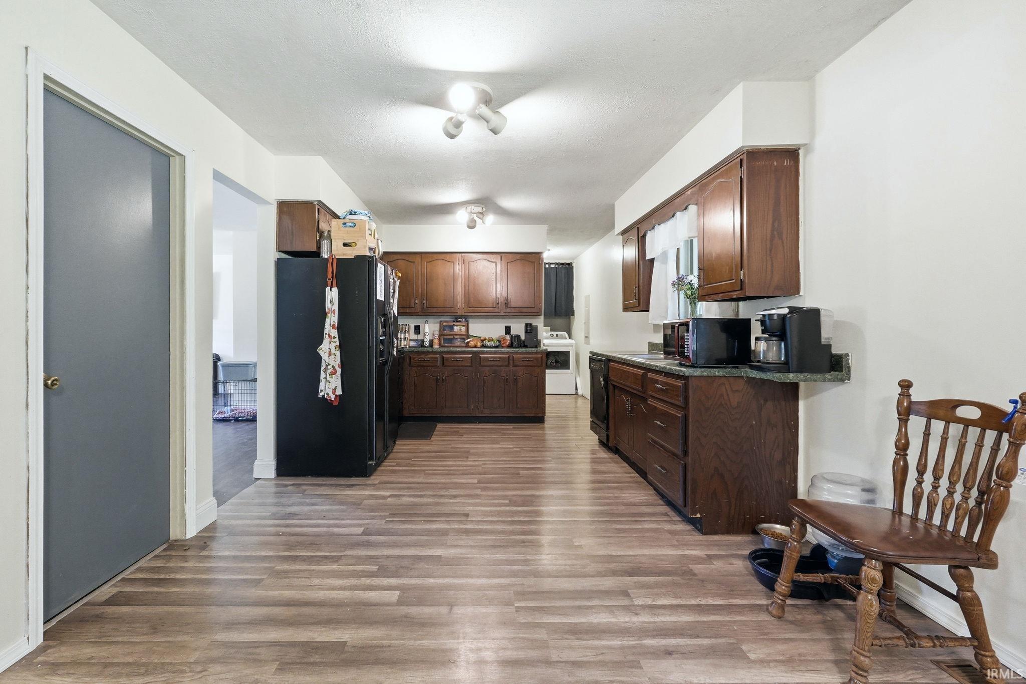 Kitchen featuring wood-finish flooring, dark wood cabinetry, and contrasting light countertops