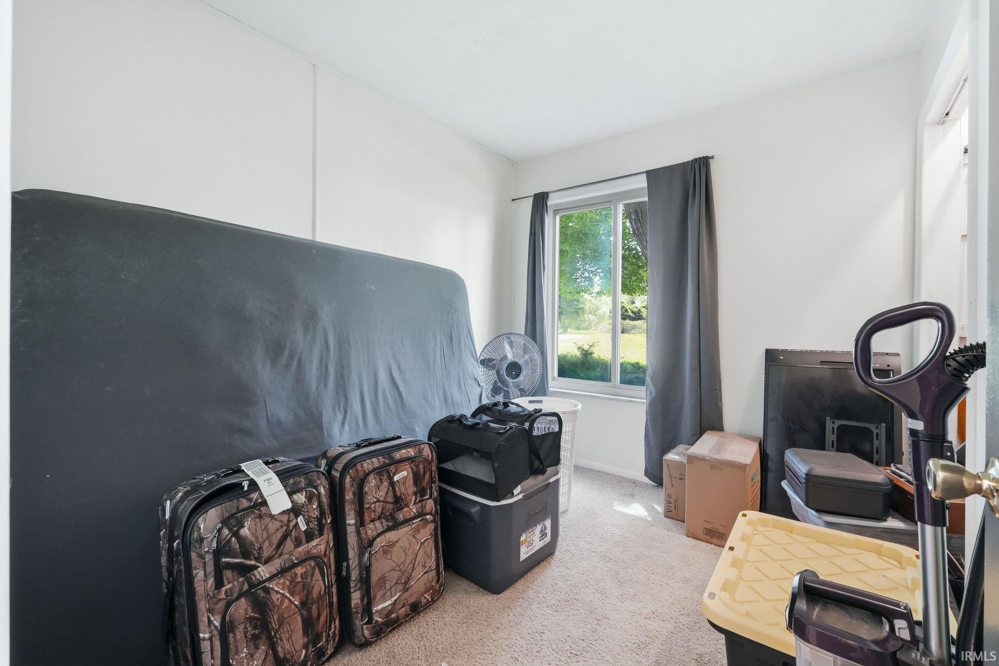 Carpeted room with a double-hung window featuring a white frame and dark grey drapes