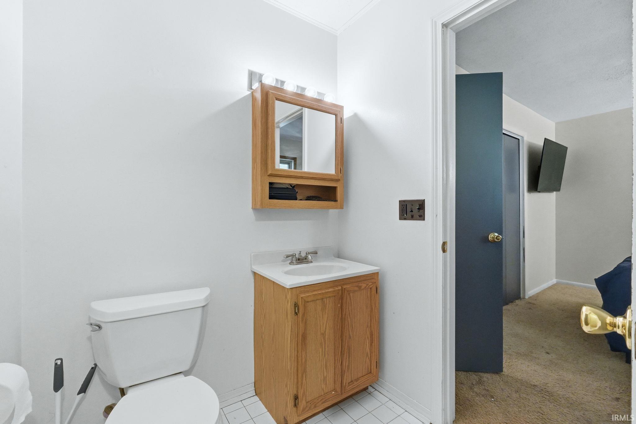 Bathroom featuring a light wood-finish vanity with an integrated sink, white countertop, and a matching mirrored medicine cabinet