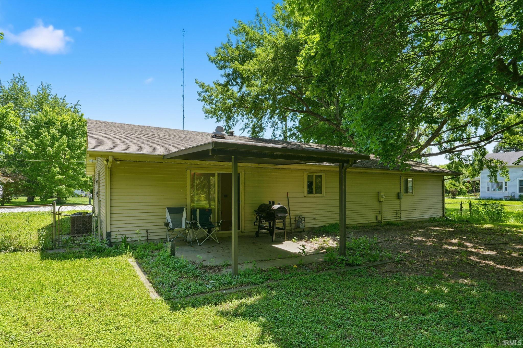Rear exterior featuring siding, an attached patio cover, a concrete patio, and a sliding glass door