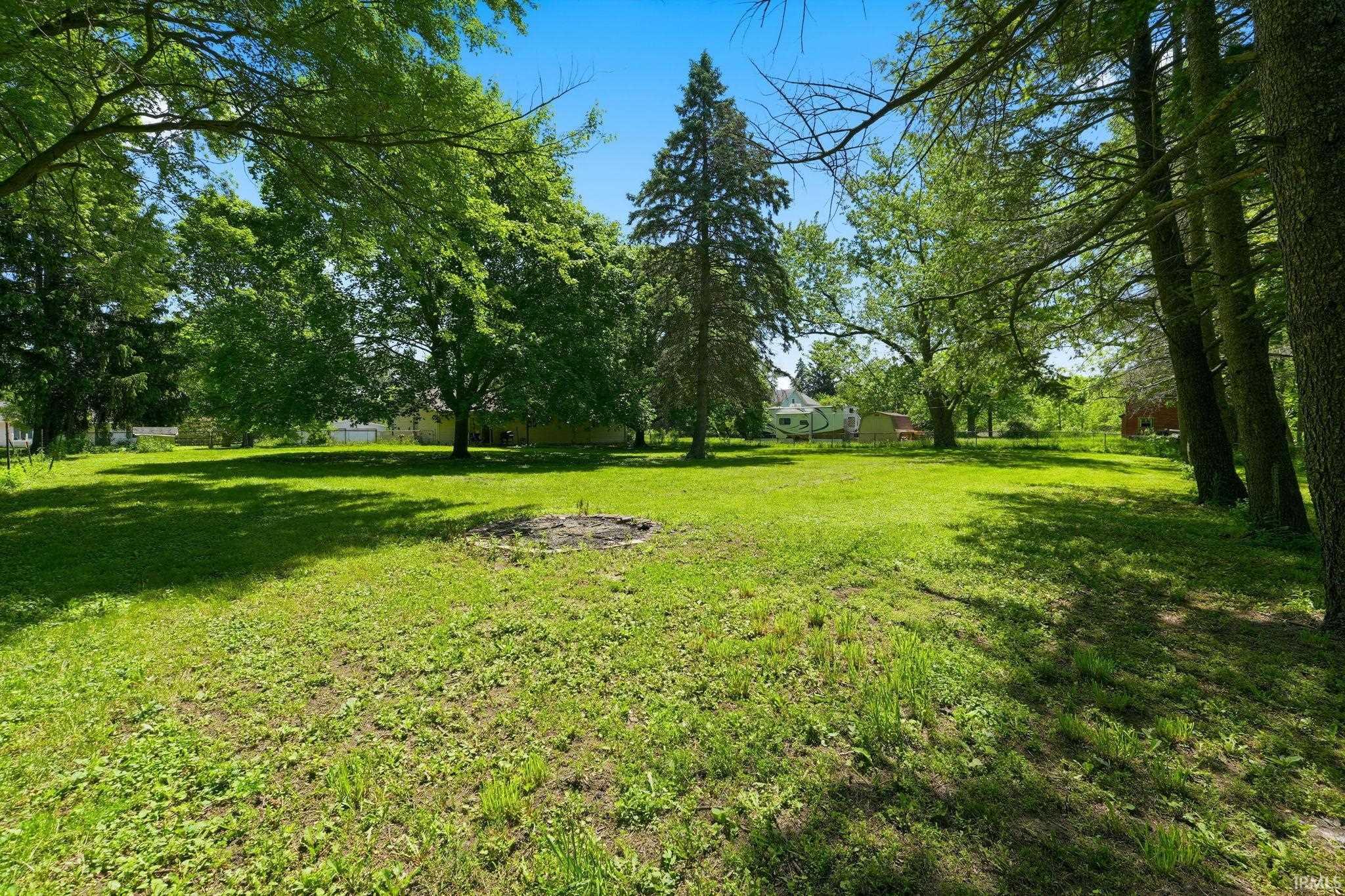 Expansive grassy yard area featuring mature trees providing natural shade
