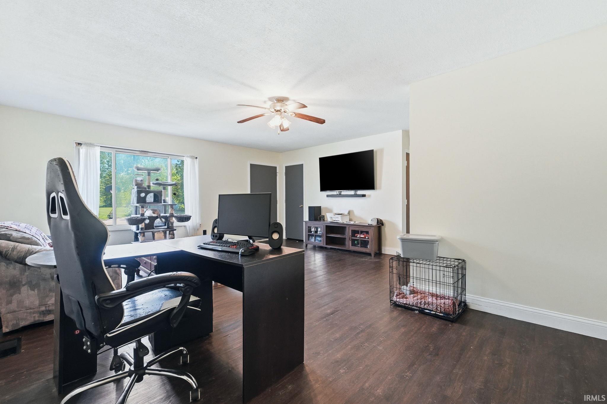 Spacious living area featuring dark wood-finish flooring and light-toned walls