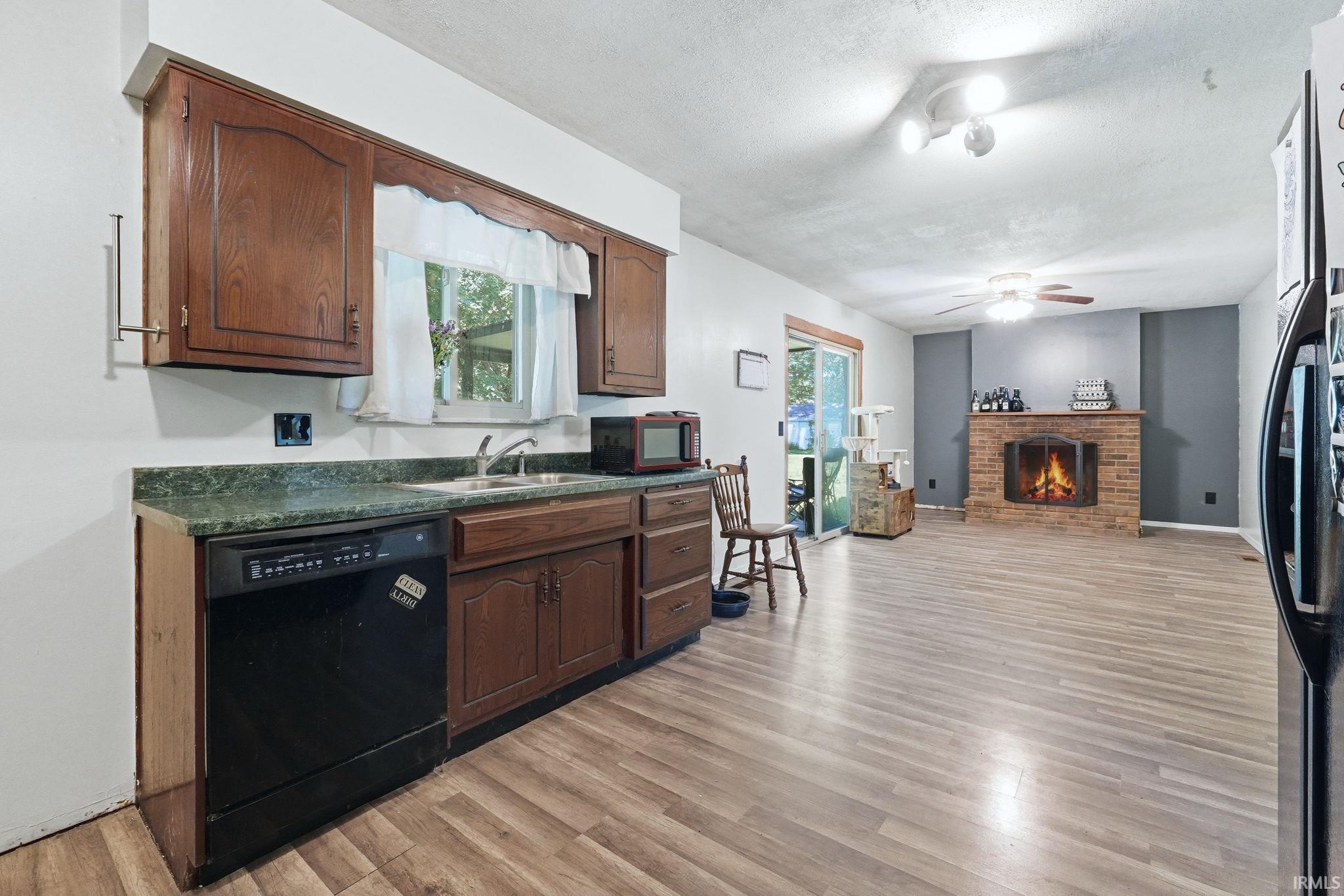 Kitchen featuring wood-finish cabinetry, a black dishwasher, and a green countertop