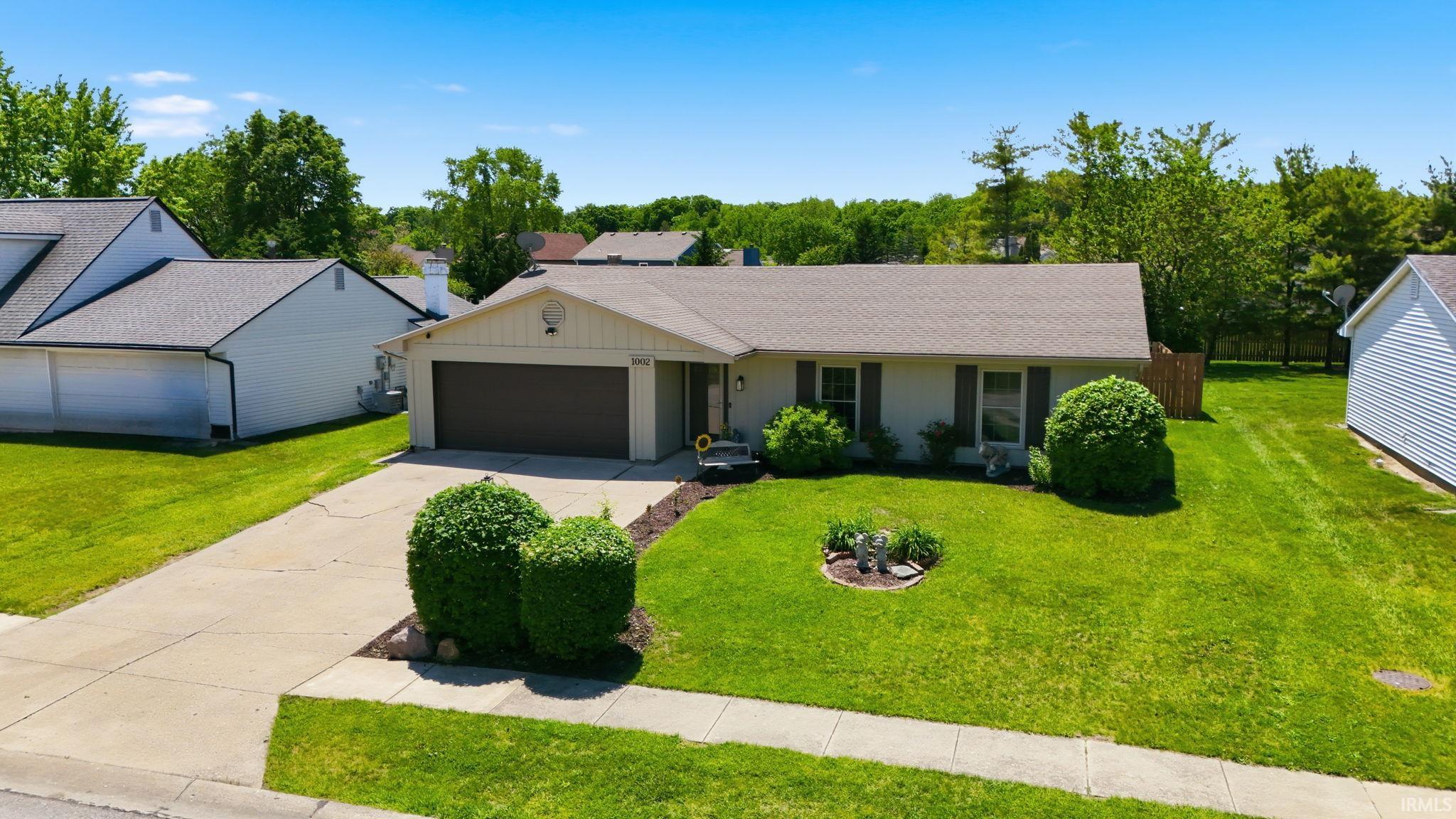 Ranch-style residence featuring a prominent front-facing garage with a dark brown door