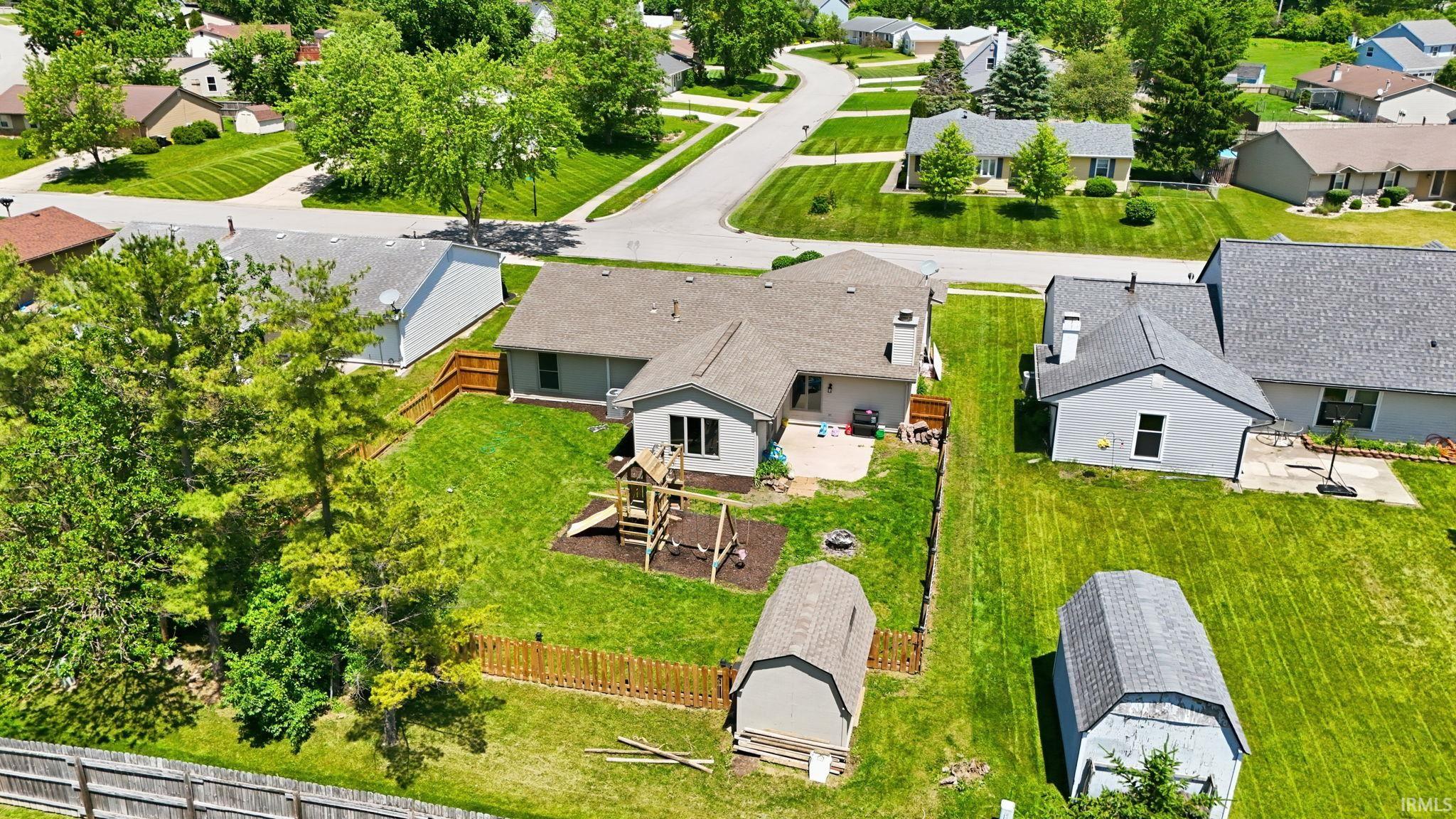 Expansive backyard featuring a manicured lawn, established trees, and perimeter fencing