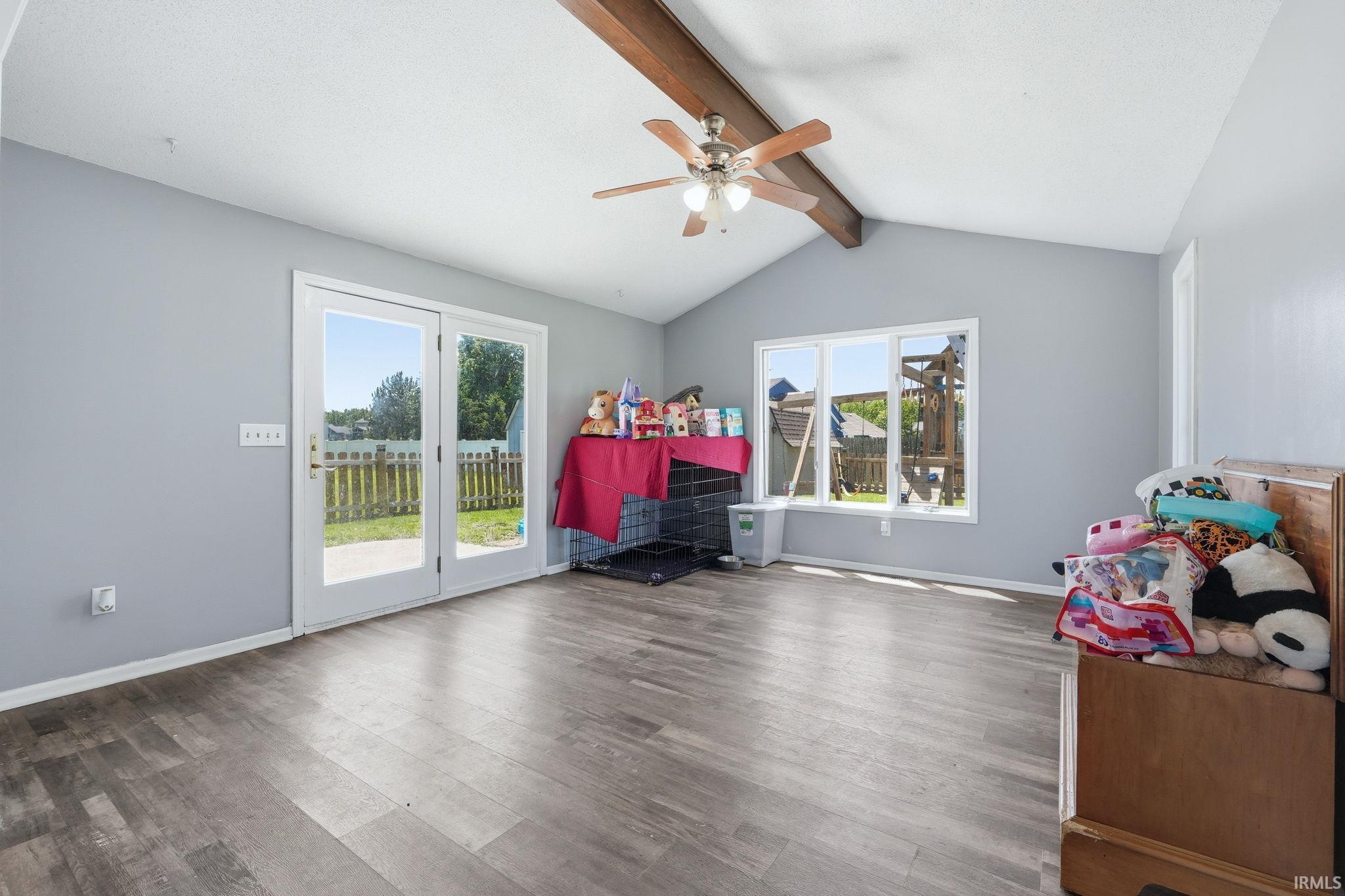 Vaulted ceiling with exposed wood beams and a ceiling fan