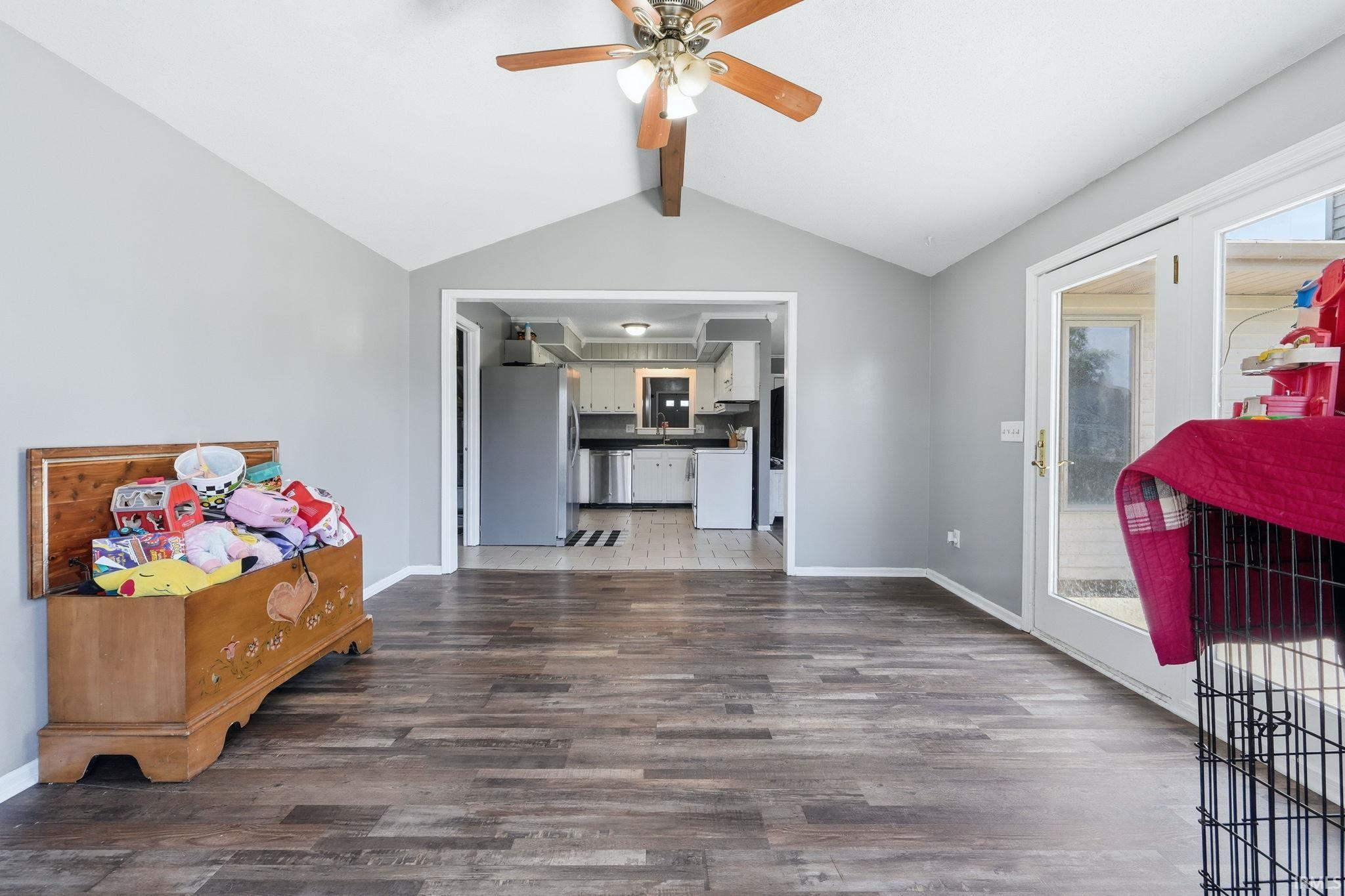 Interior space featuring wood-finish flooring, vaulted ceiling, and a ceiling fan with integrated lighting