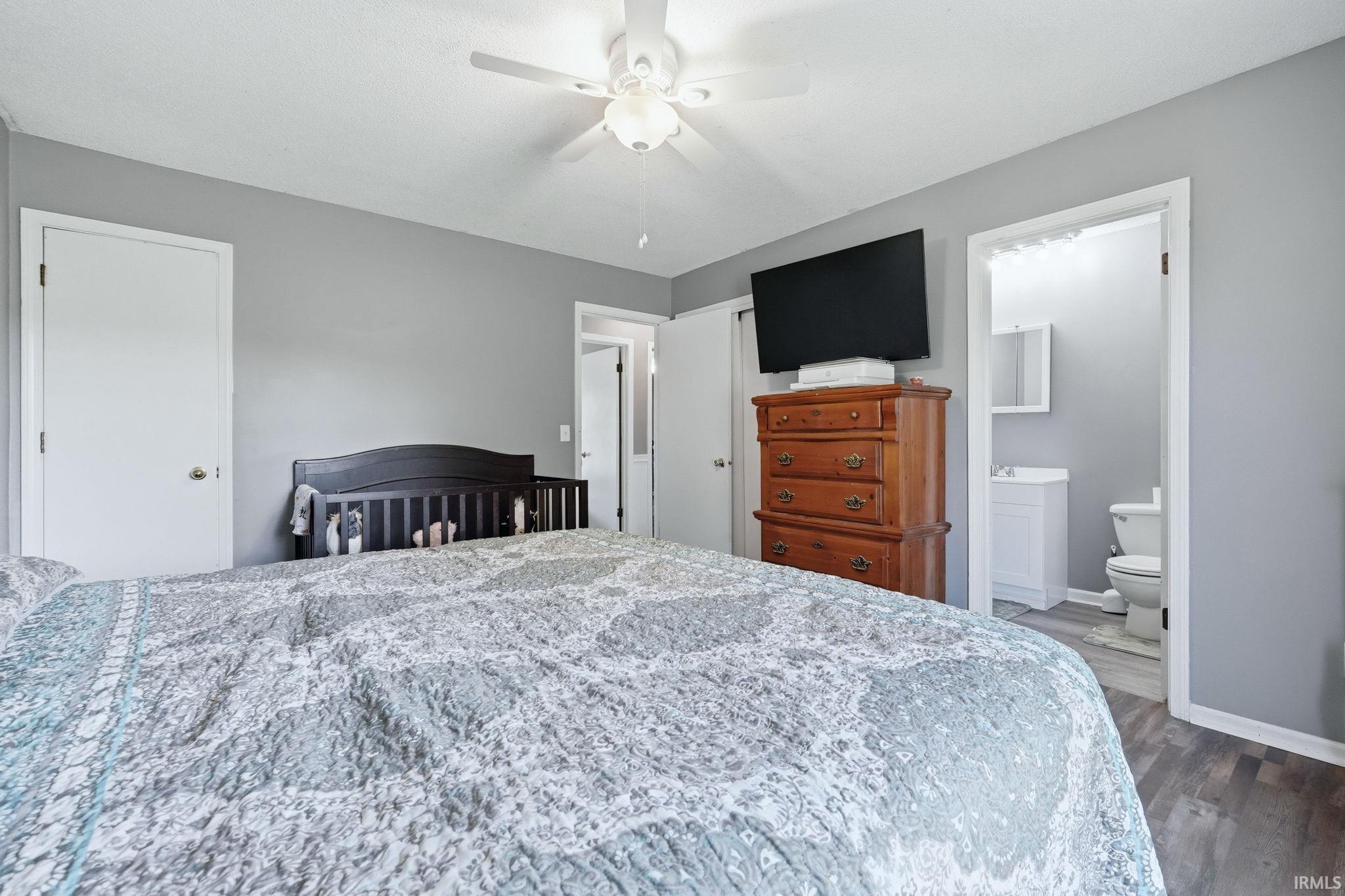 Bedroom featuring a ceiling fan with light fixture, light gray wall paint, and wood-finish flooring